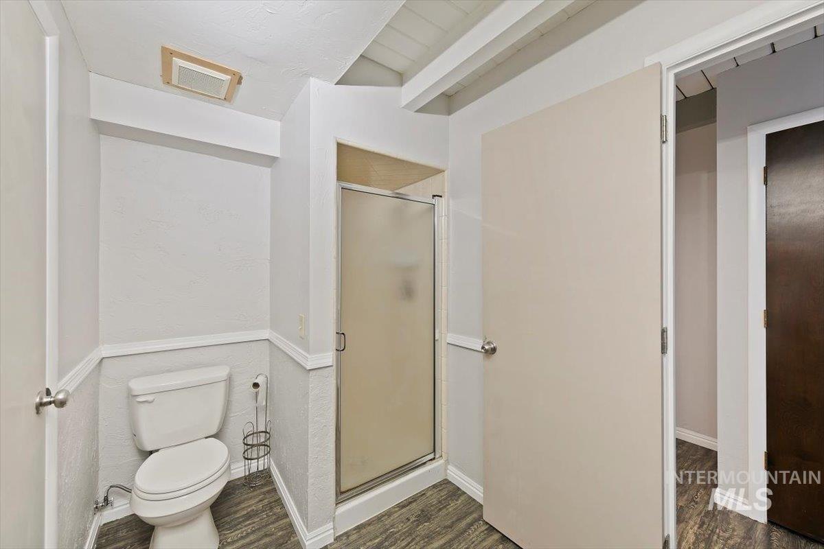 Full bathroom featuring a shower stall, dark wood-type flooring, and beamed ceiling