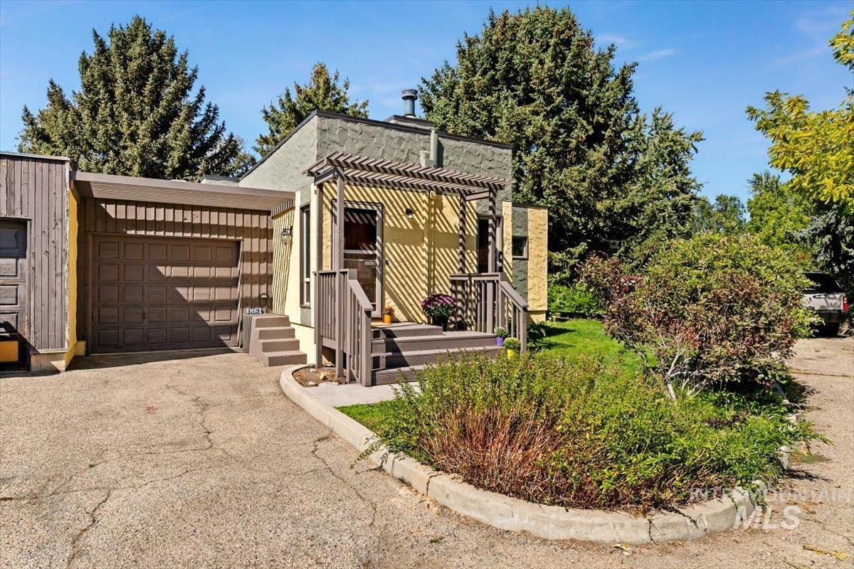 View of front of property featuring a garage, asphalt driveway, and stucco siding