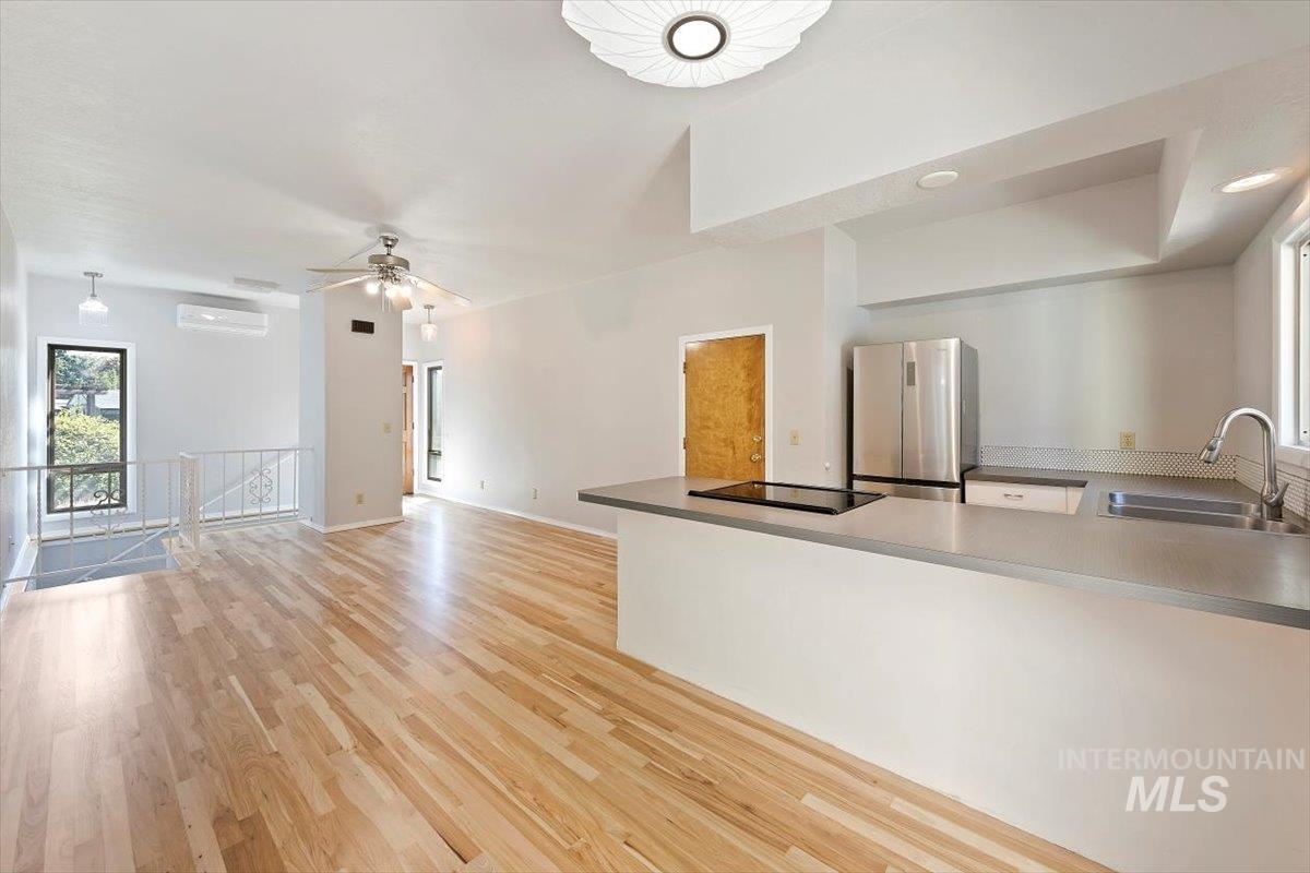 Unfurnished living room featuring plenty of natural light, light wood-style flooring, ceiling fan, an AC wall unit, and recessed lighting