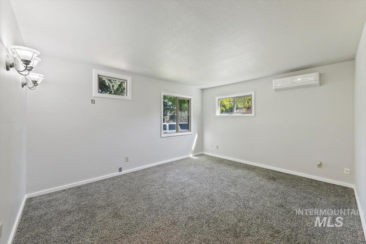 Spare room with carpet flooring, plenty of natural light, a textured ceiling, and a wall mounted air conditioner