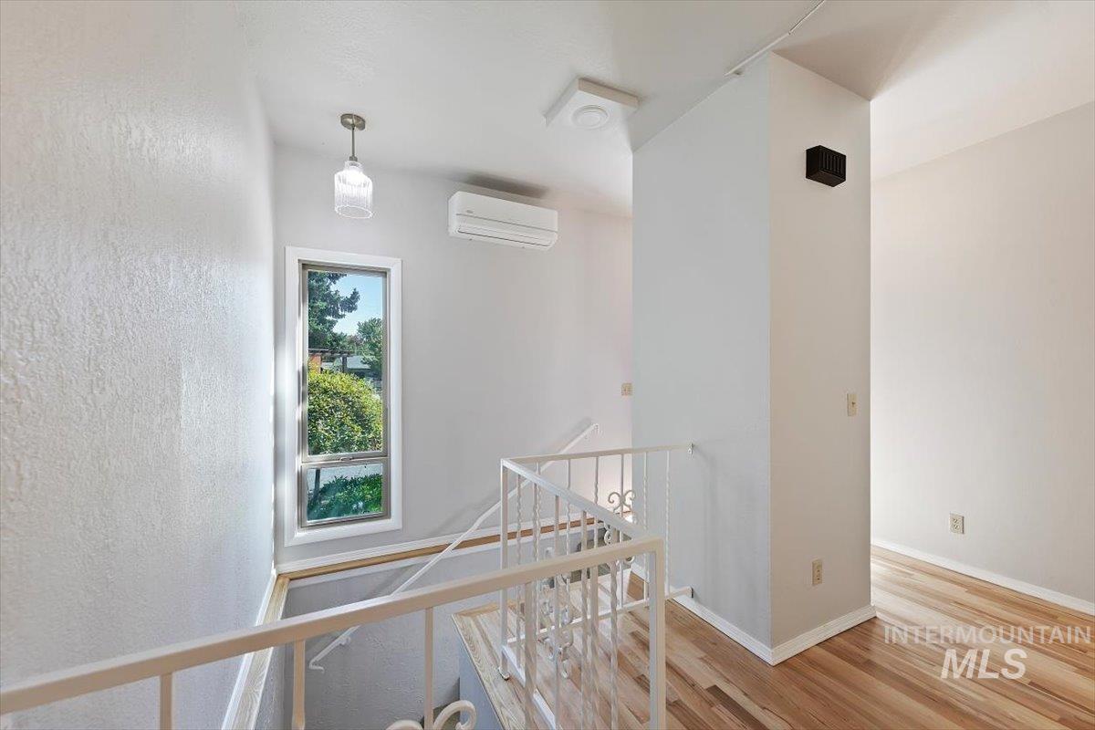 Hall featuring an upstairs landing, wood finished floors, and a wall mounted air conditioner