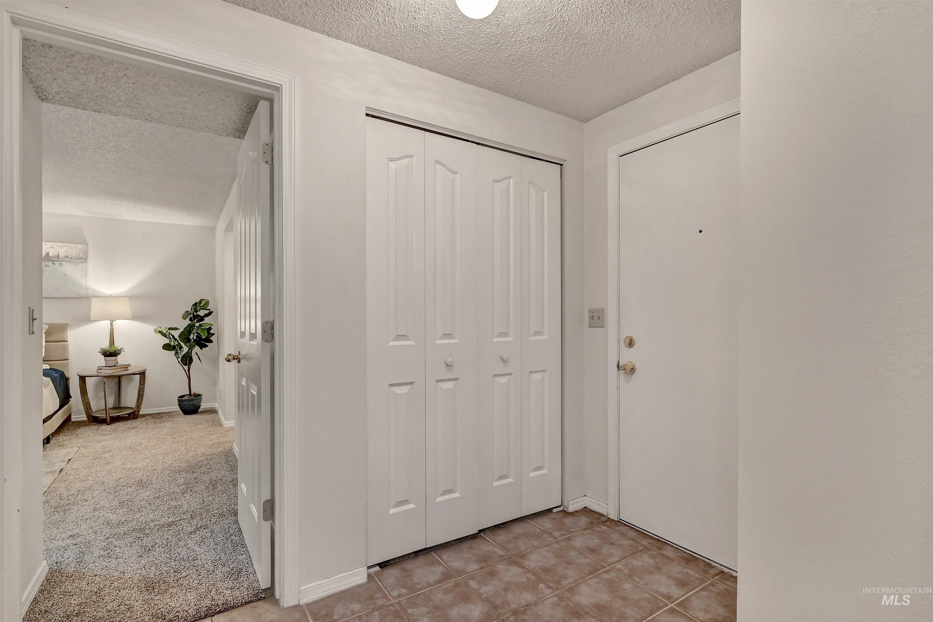 Foyer entrance with a textured ceiling, washer / clothes dryer, light tile patterned flooring, and light carpet