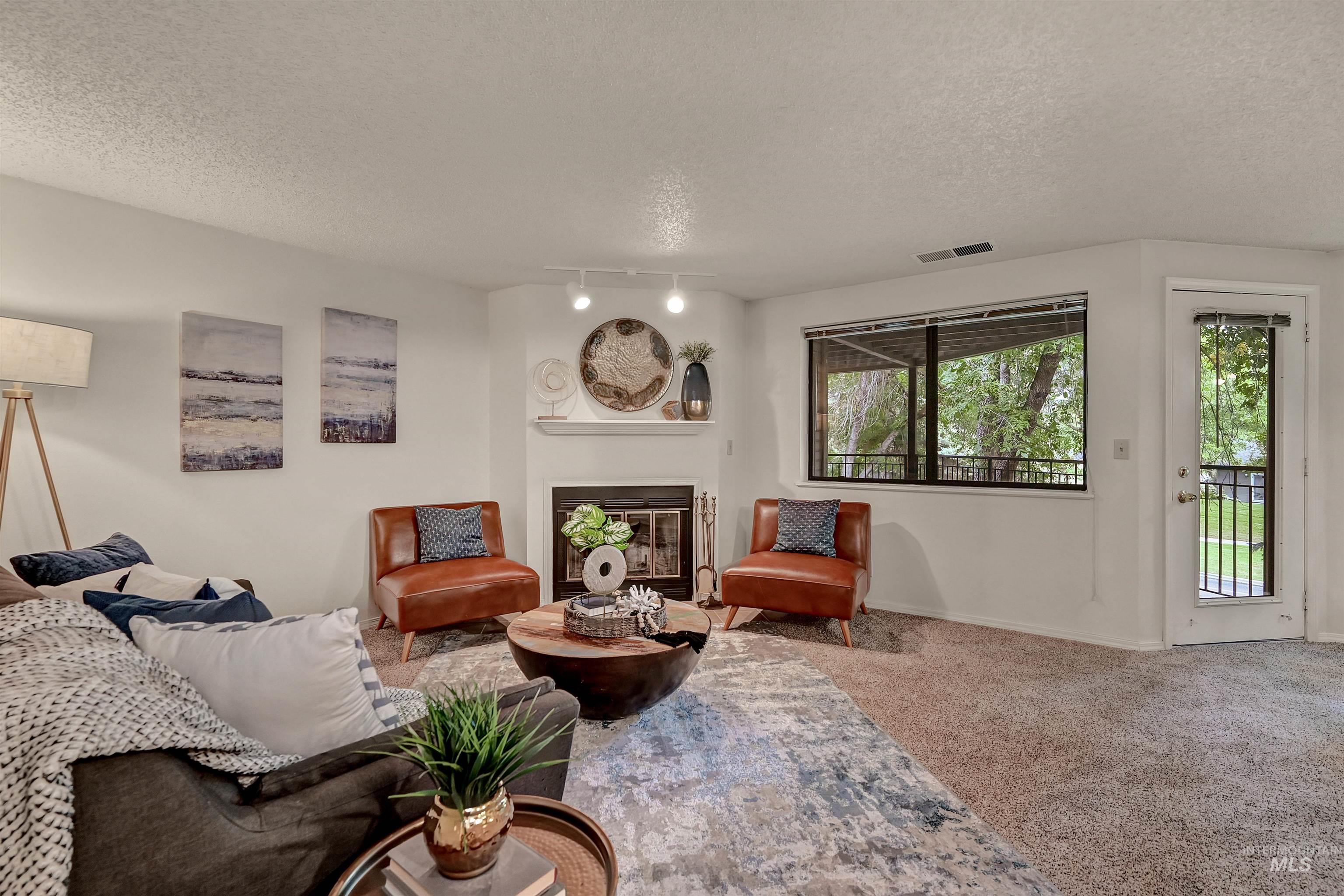 Carpeted living area with a glass covered fireplace and a textured ceiling