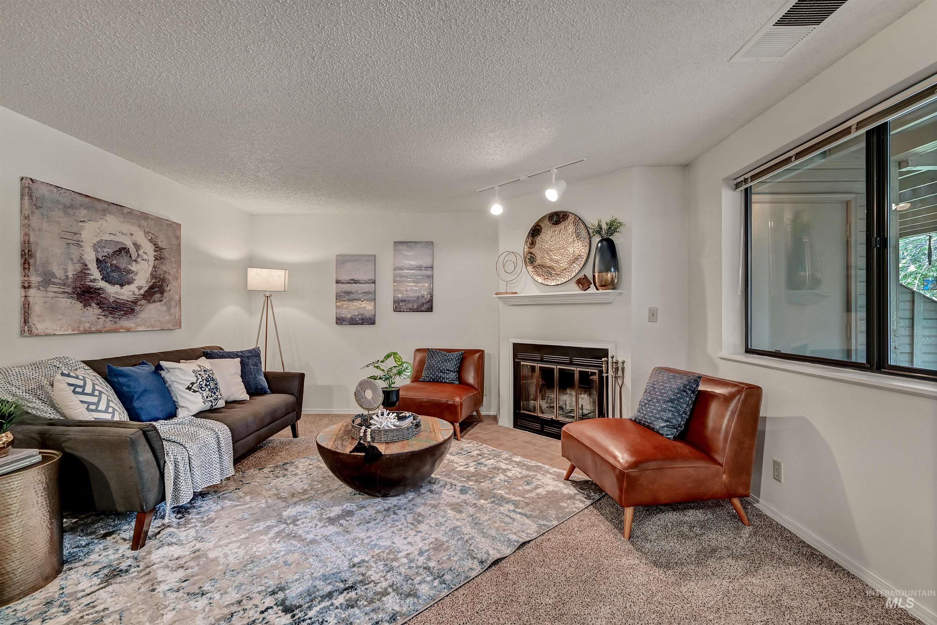 Living room featuring a glass covered fireplace, carpet, and a textured ceiling