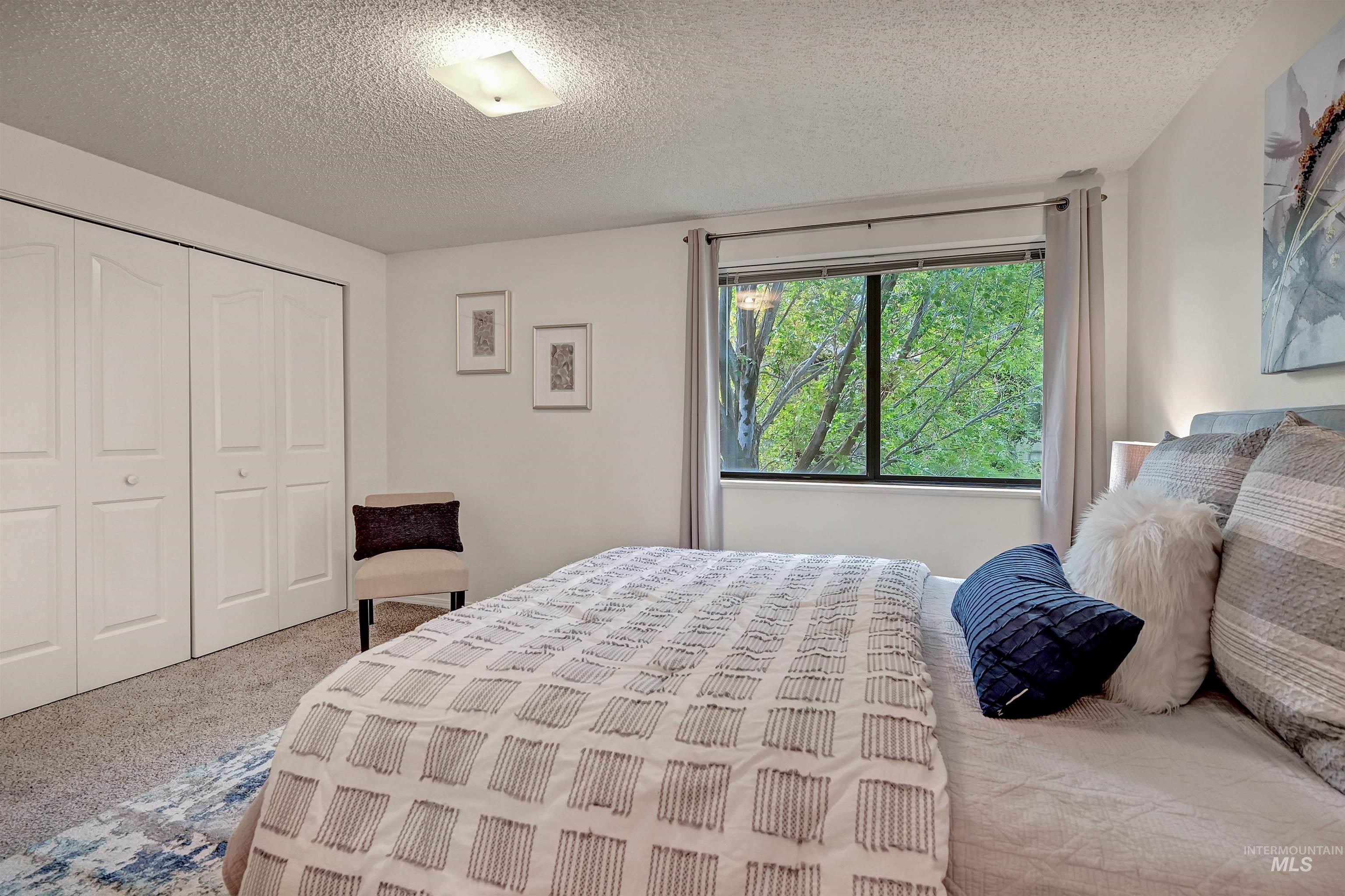 Bedroom with carpet floors, a closet, and a textured ceiling