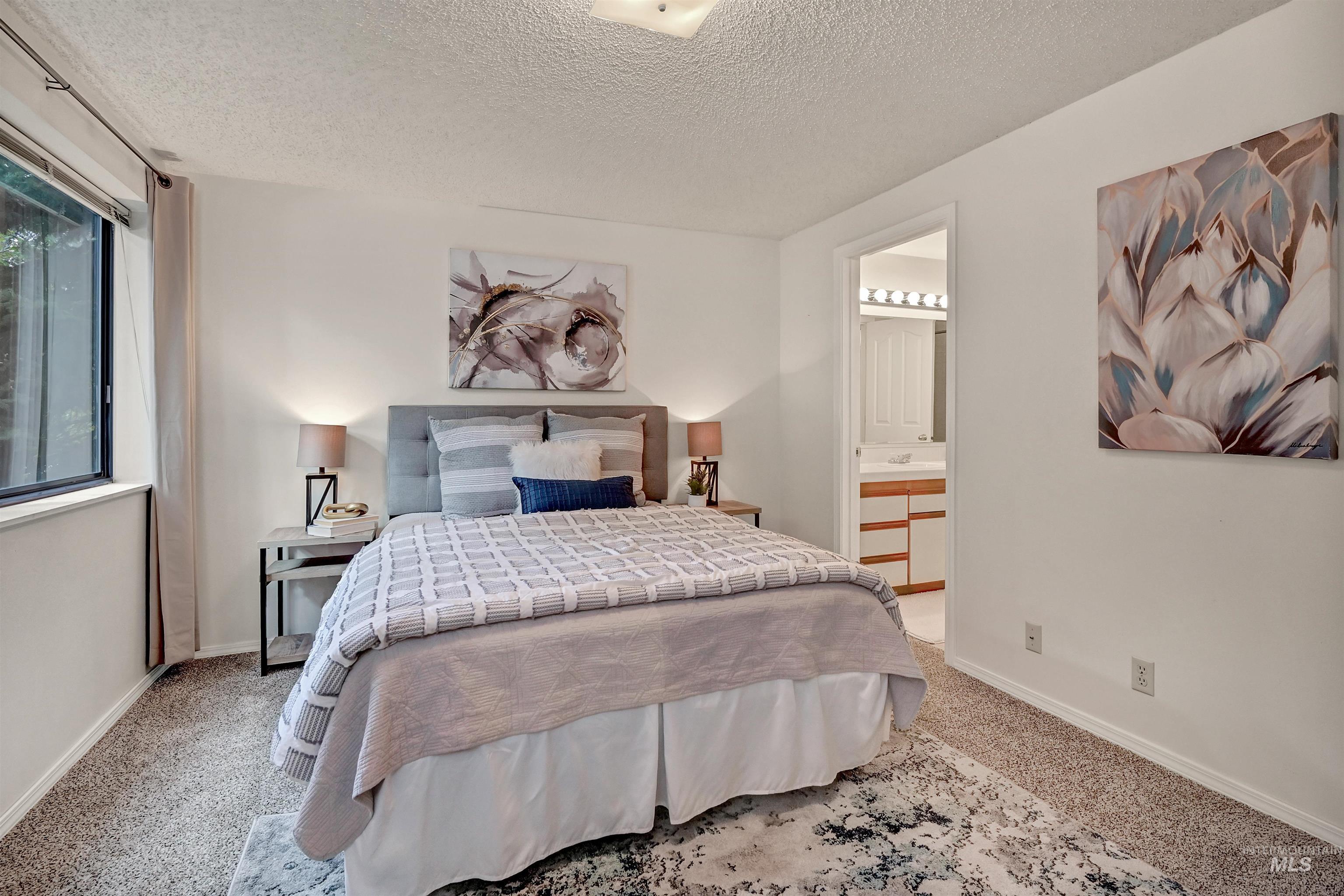 Carpeted bedroom featuring a textured ceiling and connected bathroom