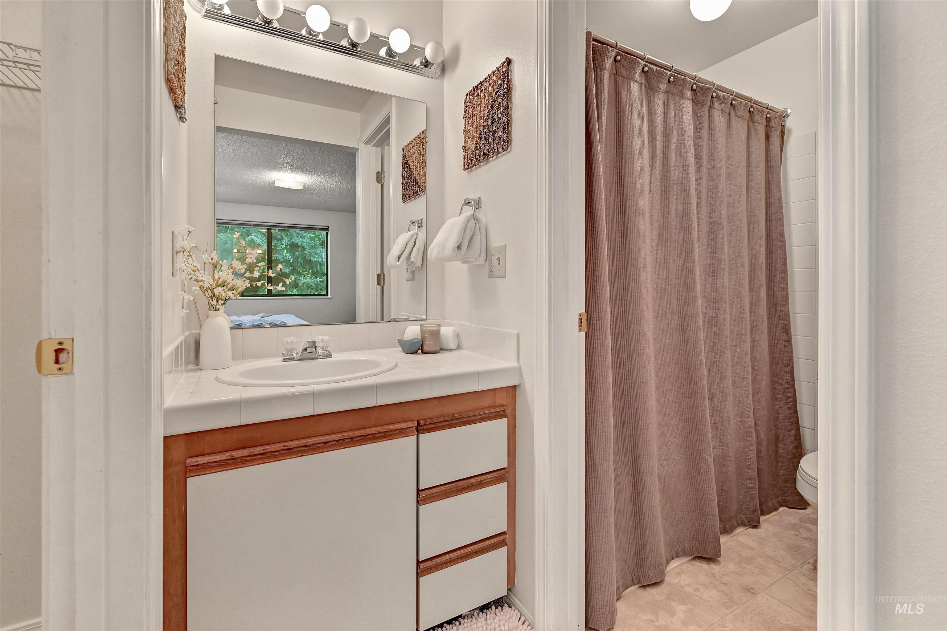Full bath featuring vanity, light tile patterned floors, and curtained shower
