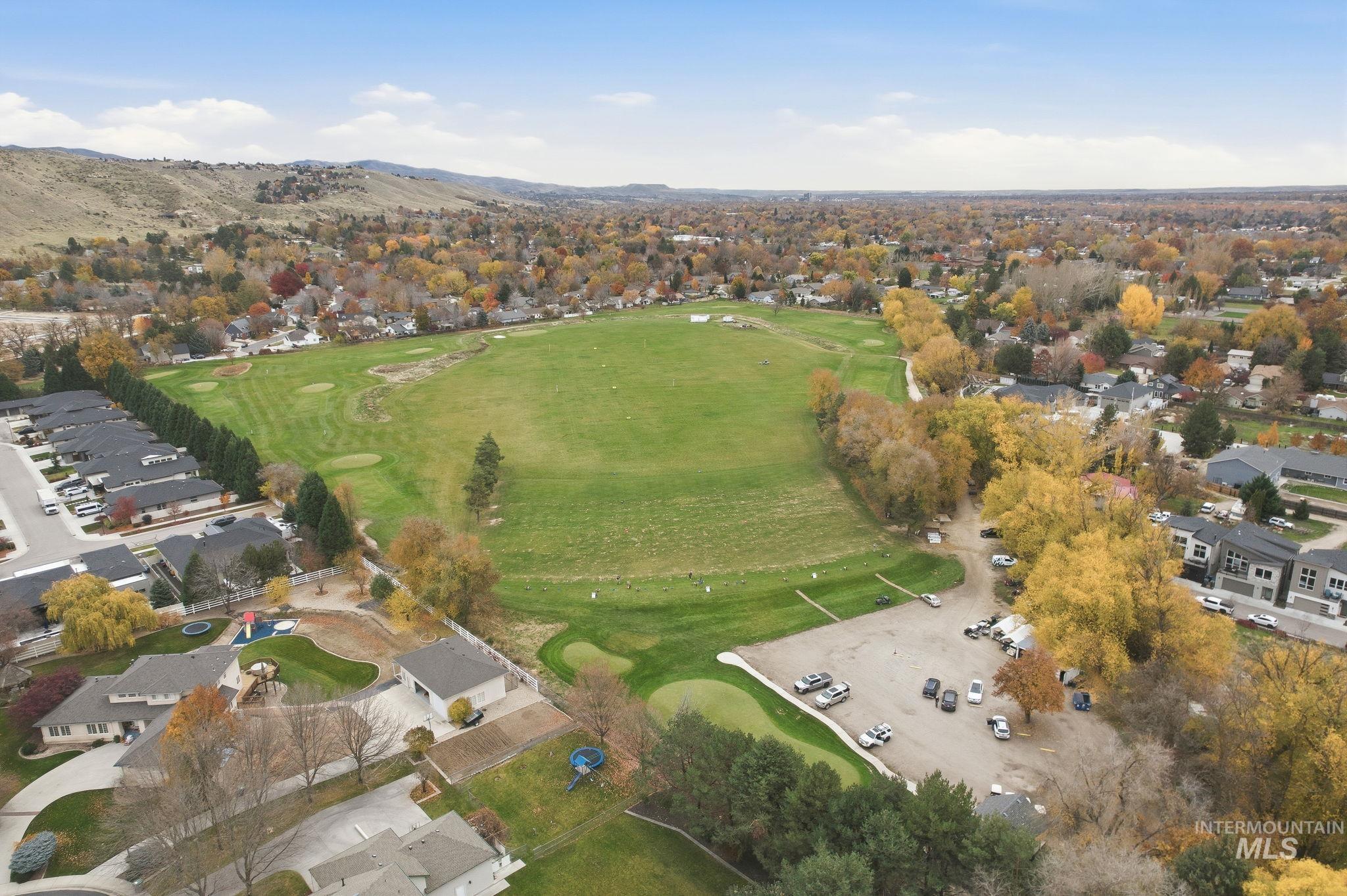 Aerial view of property's location featuring nearby suburban area, a mountain backdrop, and a golf course