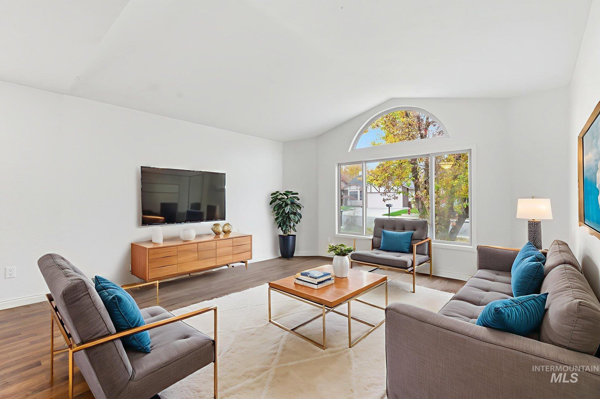 Virtually staged living area with vaulted ceiling and wood finished floors