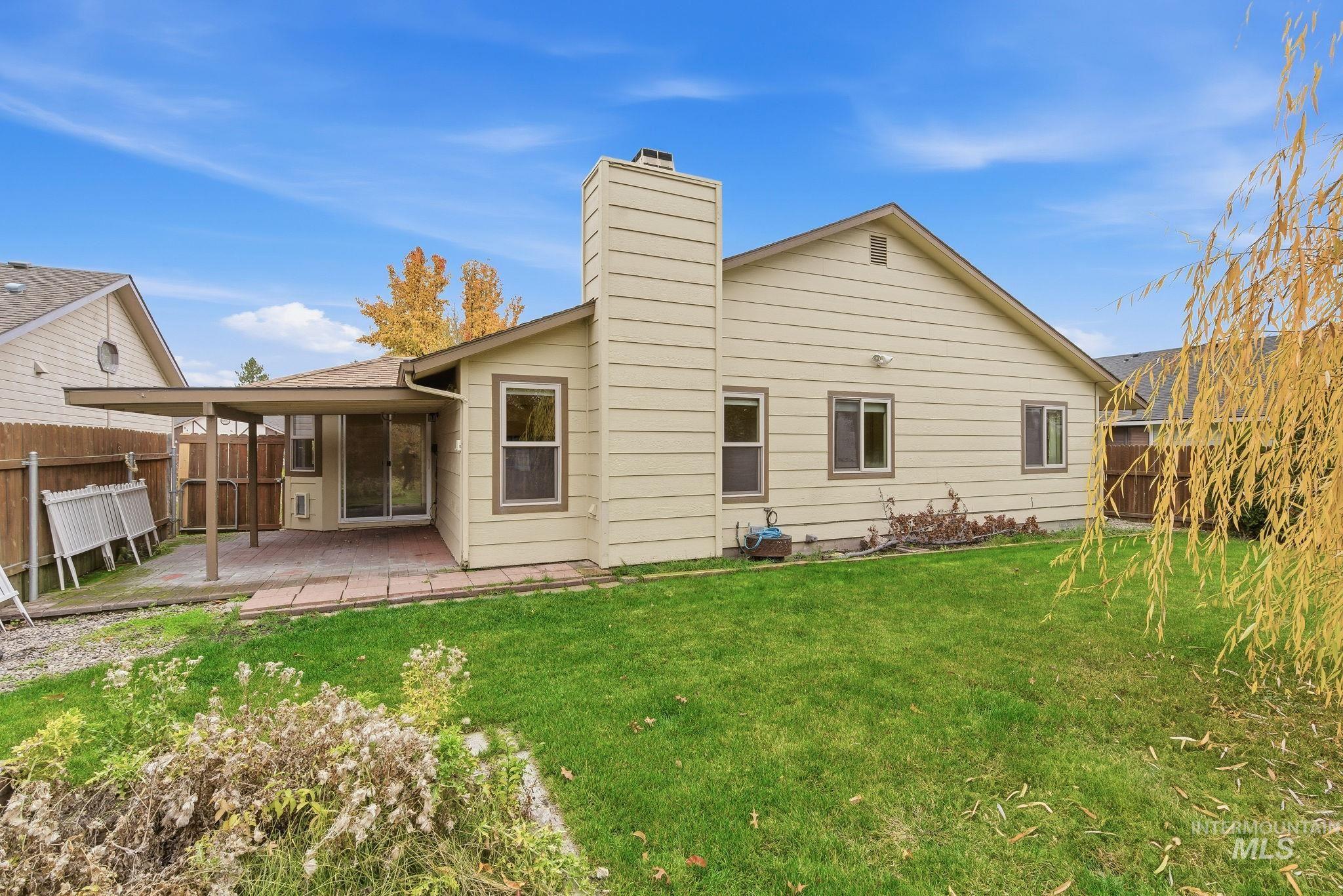 Back of property with a fenced backyard, a chimney, and a patio area