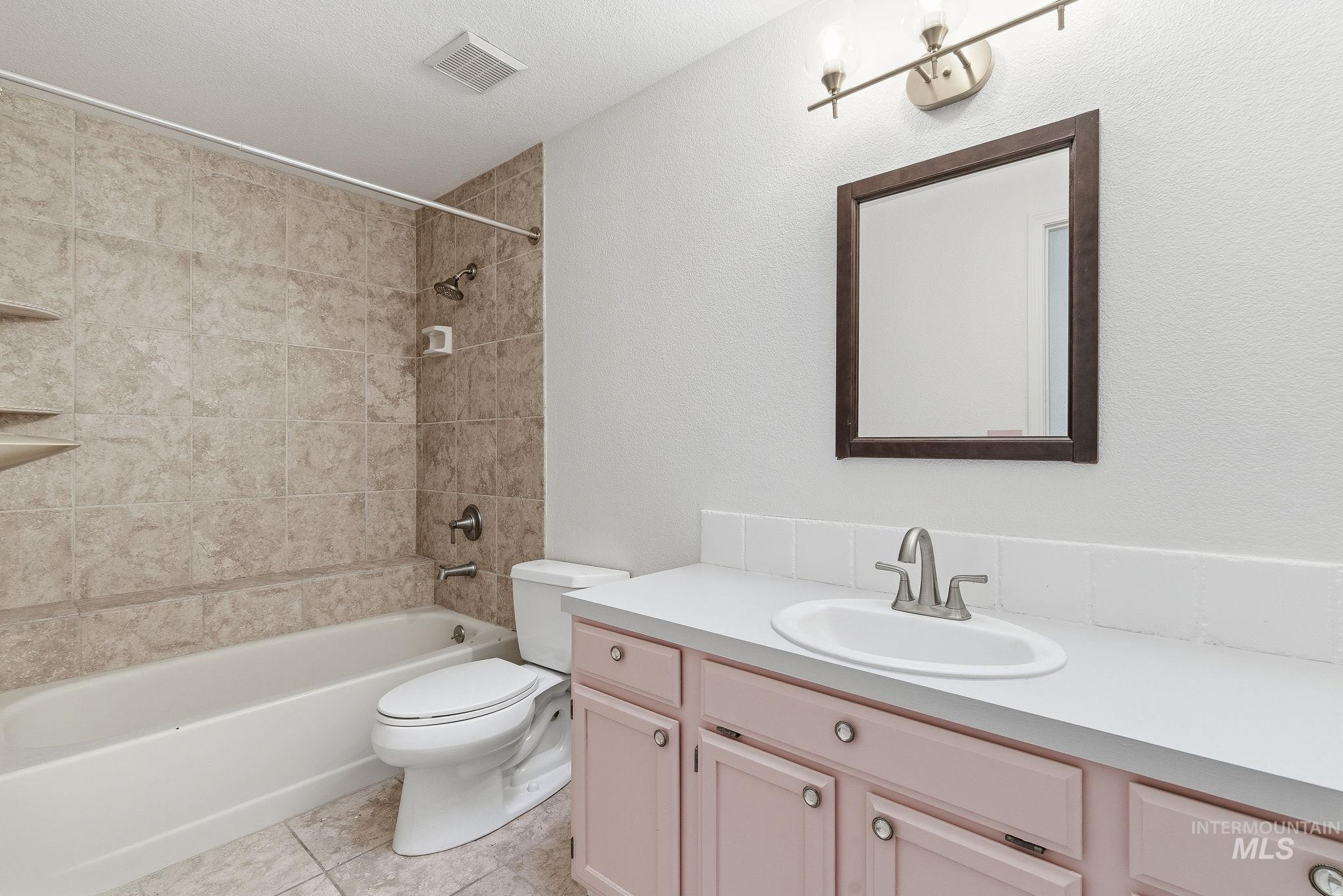Bathroom with tub / shower combination, vanity, and light tile patterned floors
