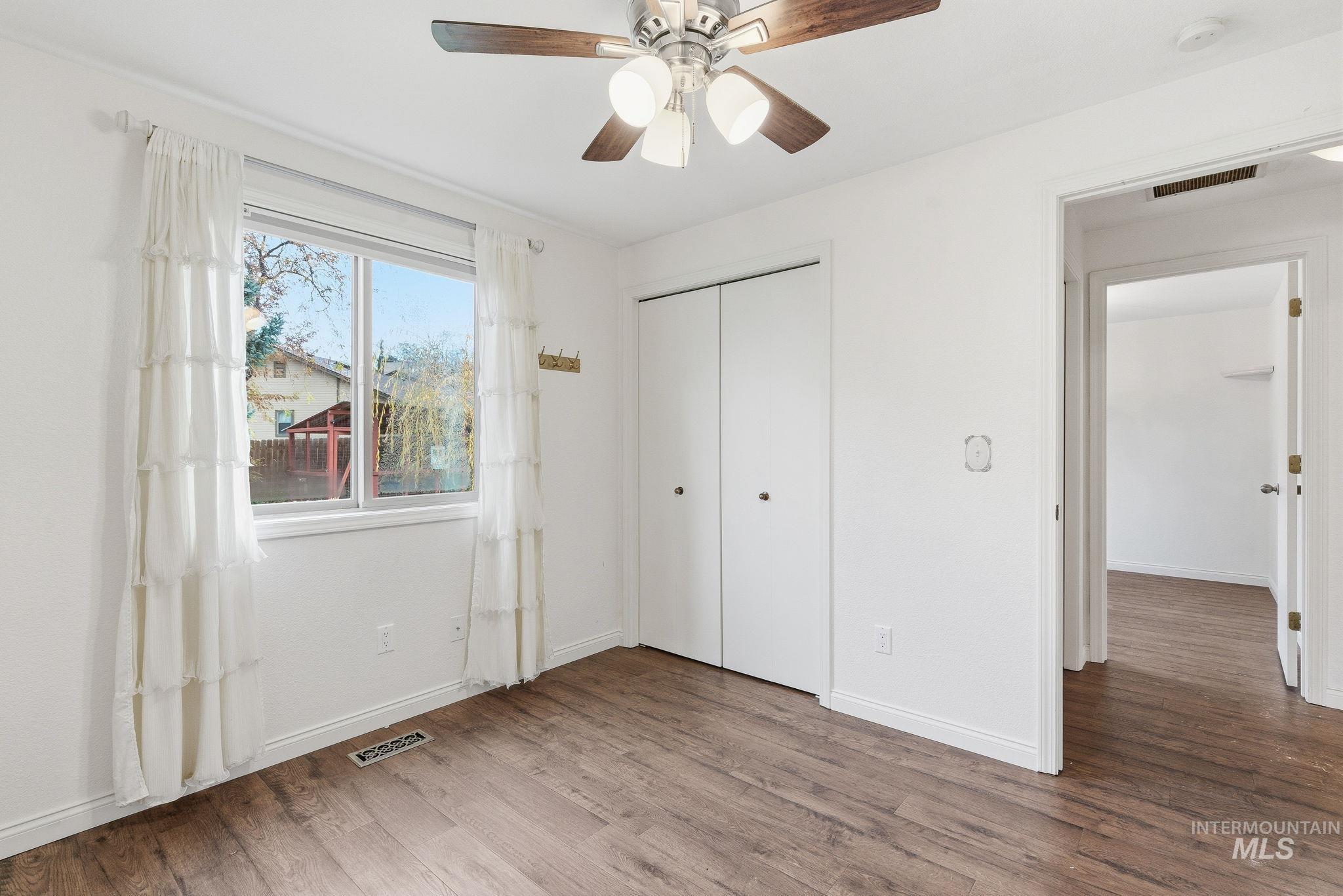 Unfurnished bedroom with wood finished floors, a closet, and a ceiling fan