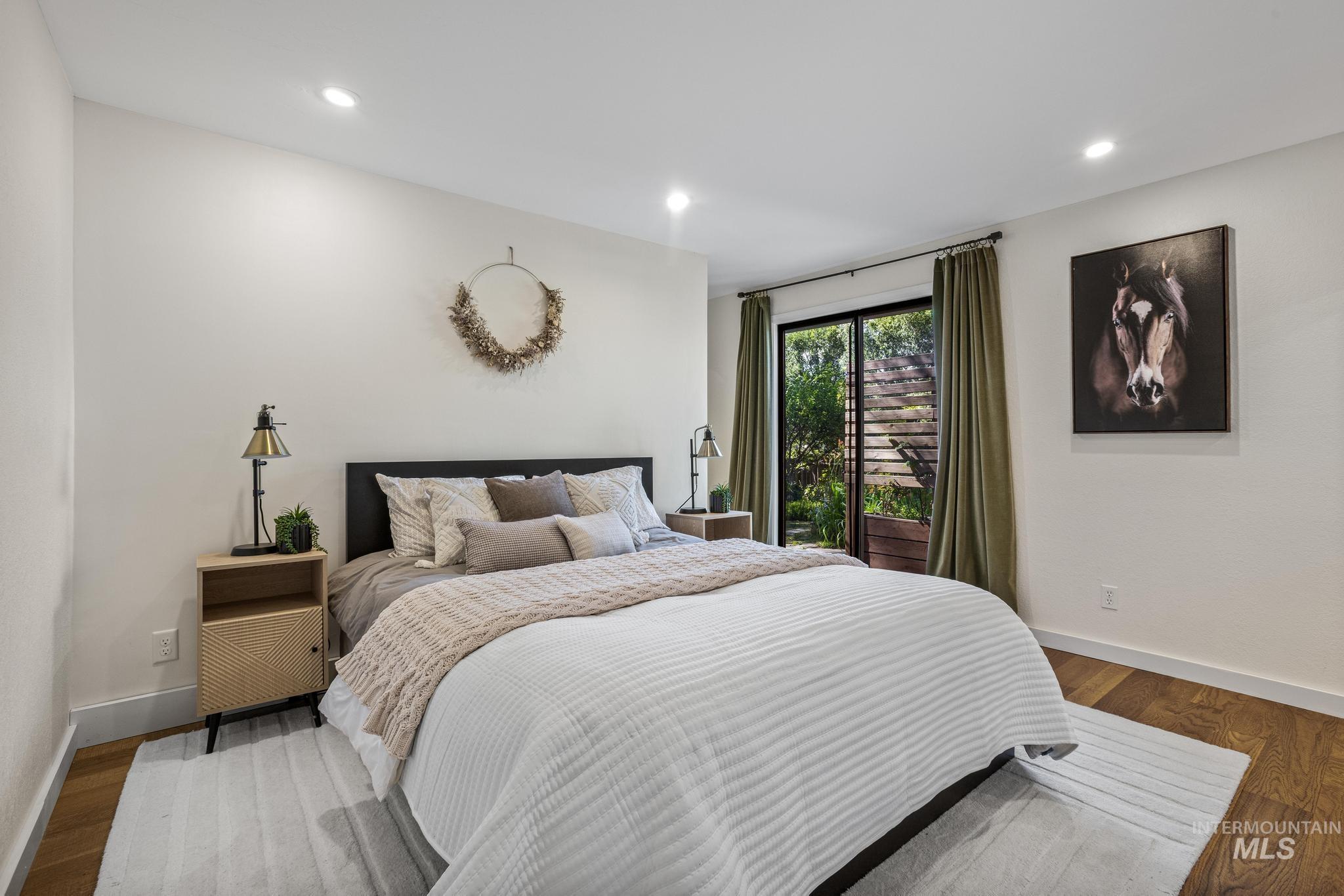 Bright living space featuring recessed lighting, wood-finish flooring, white baseboards, a black headboard, and sliding glass doors