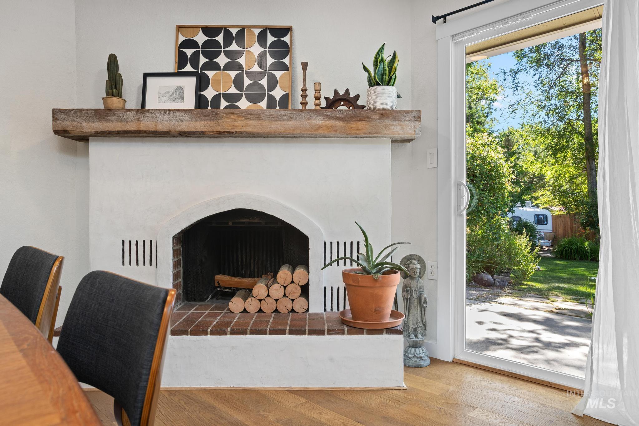 White stucco fireplace with a substantial wood mantel, brick hearth, and arched firebox opening