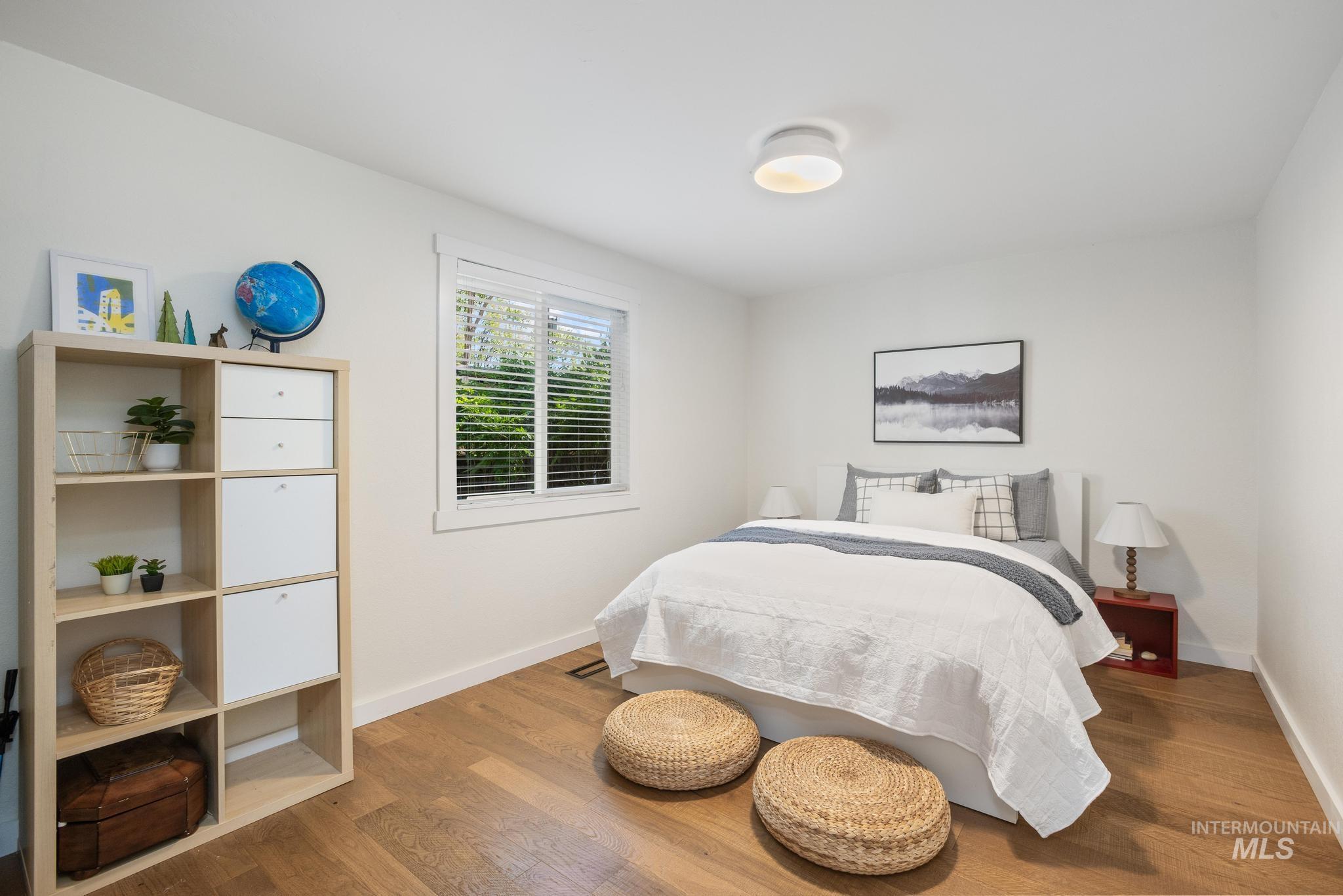 Bright interior featuring wood-finish flooring, white walls, and a window with blinds