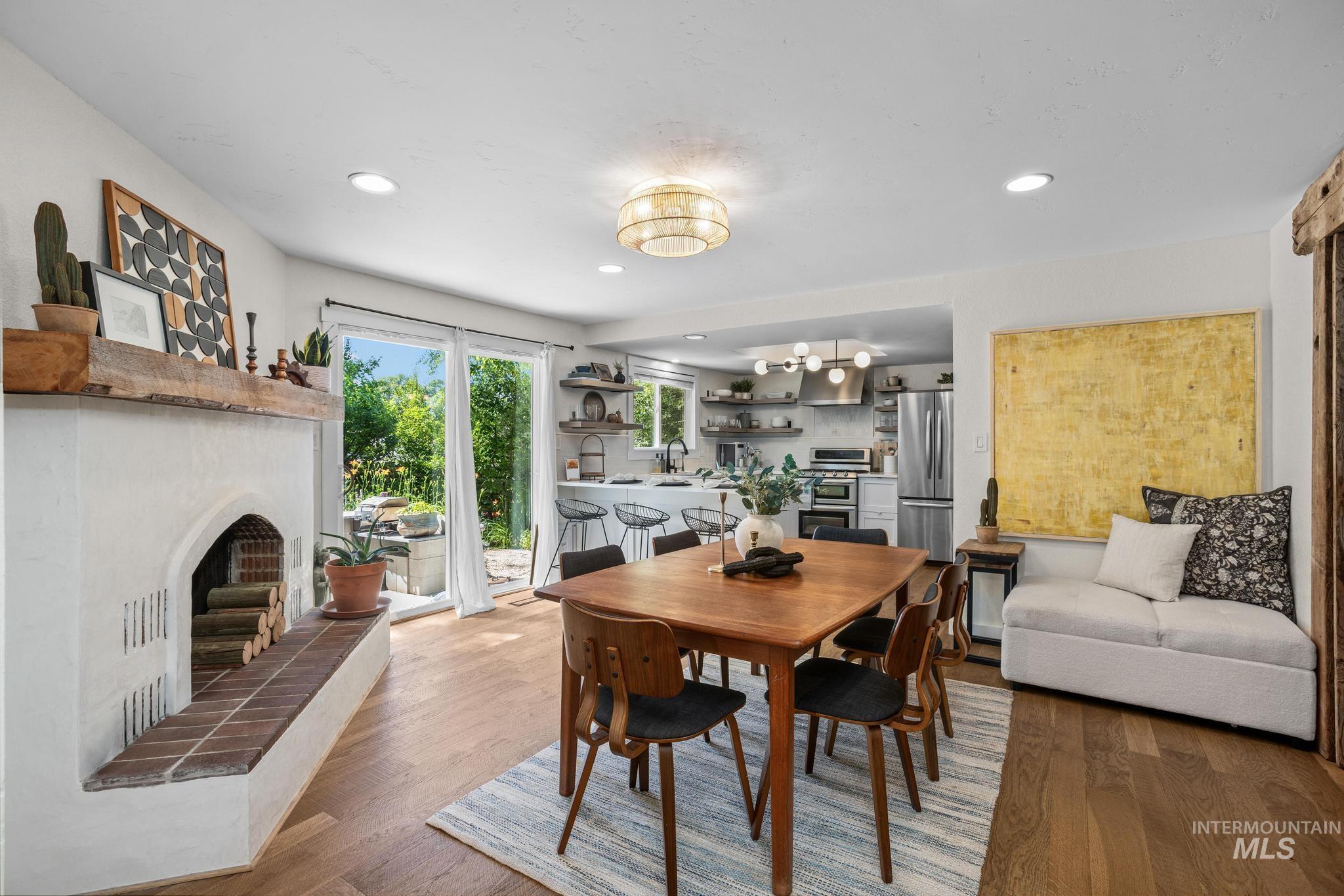 Spacious dining area featuring wood-finish flooring and a white plaster fireplace with a rustic wood mantel