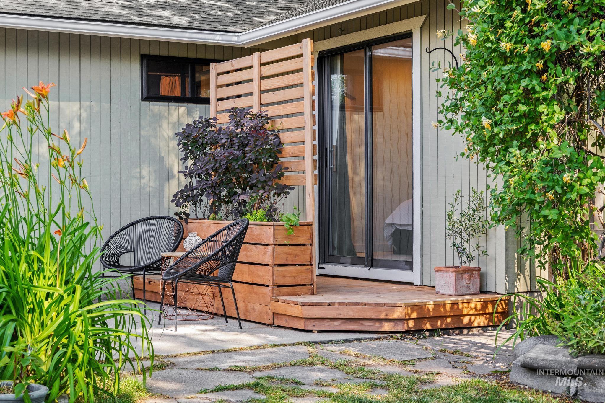 Outdoor patio featuring a privacy screen, a raised planter box, wood decking, a sliding glass door, and board and batten siding