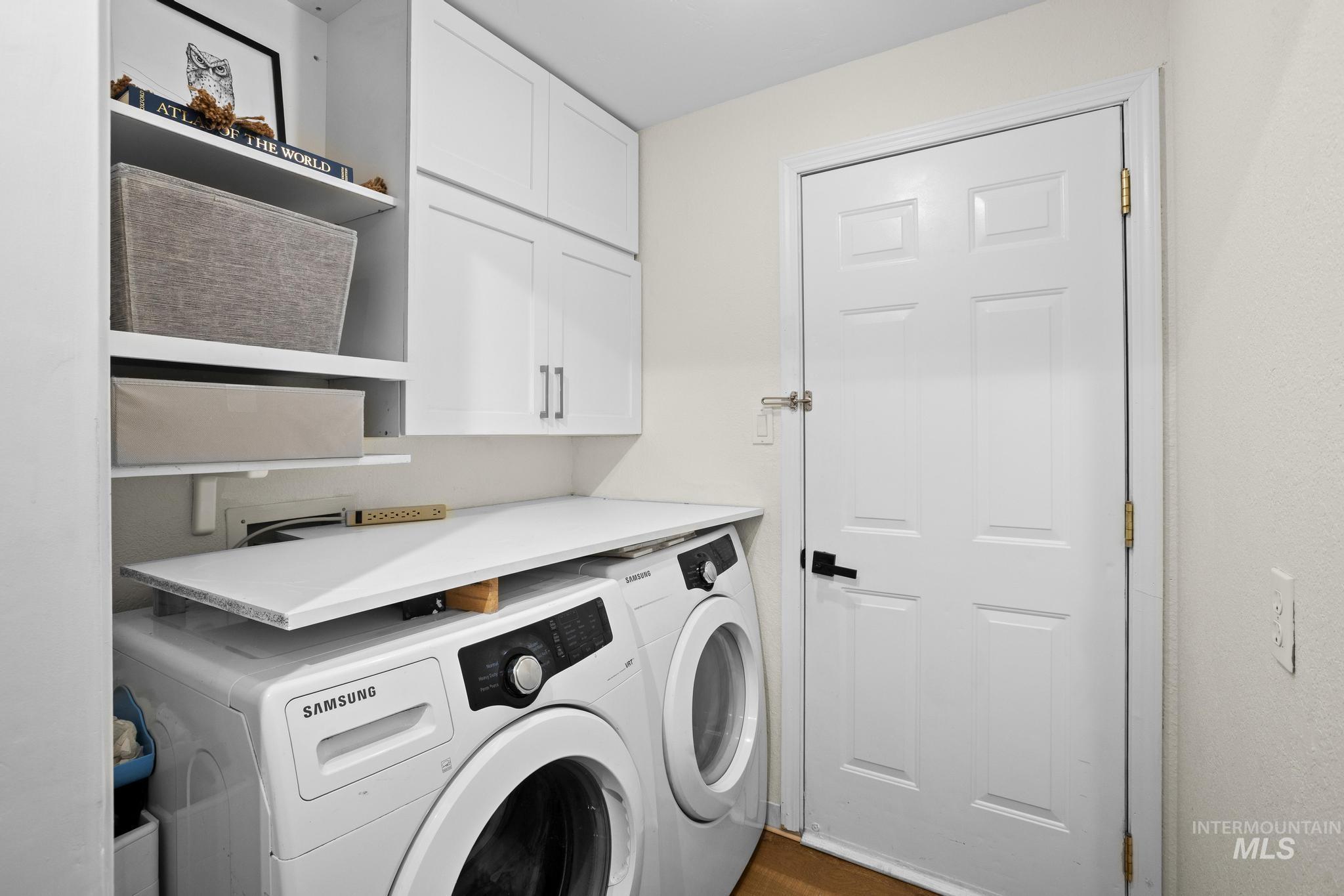 Laundry area featuring white cabinetry, open shelving, a white countertop, and a paneled white door