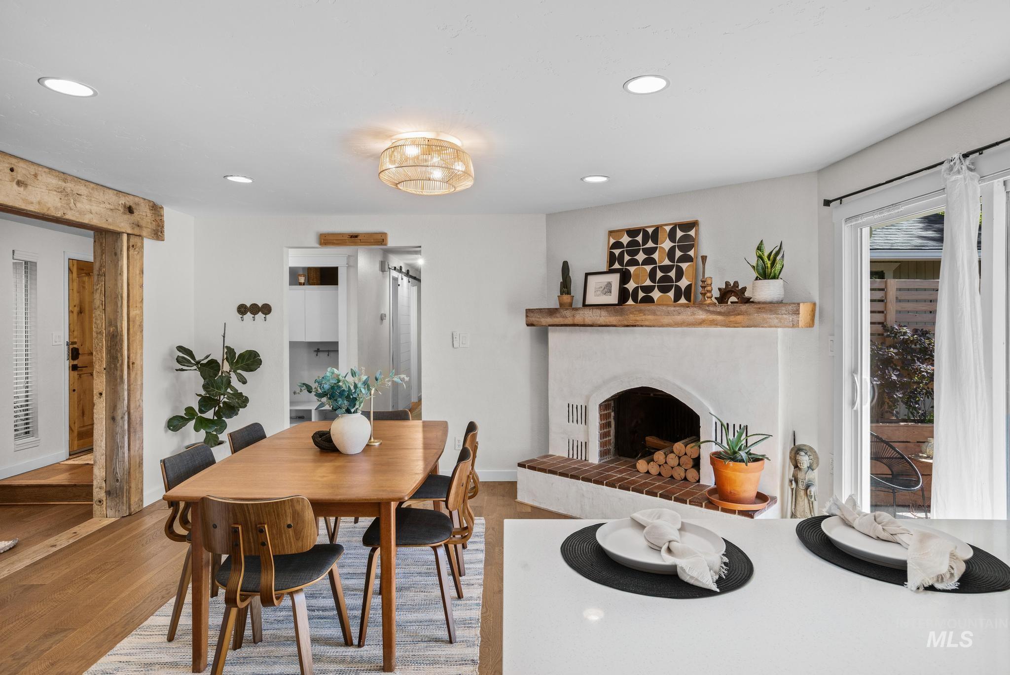 Dining area featuring wood-finish flooring and a white brick fireplace with a wood mantle