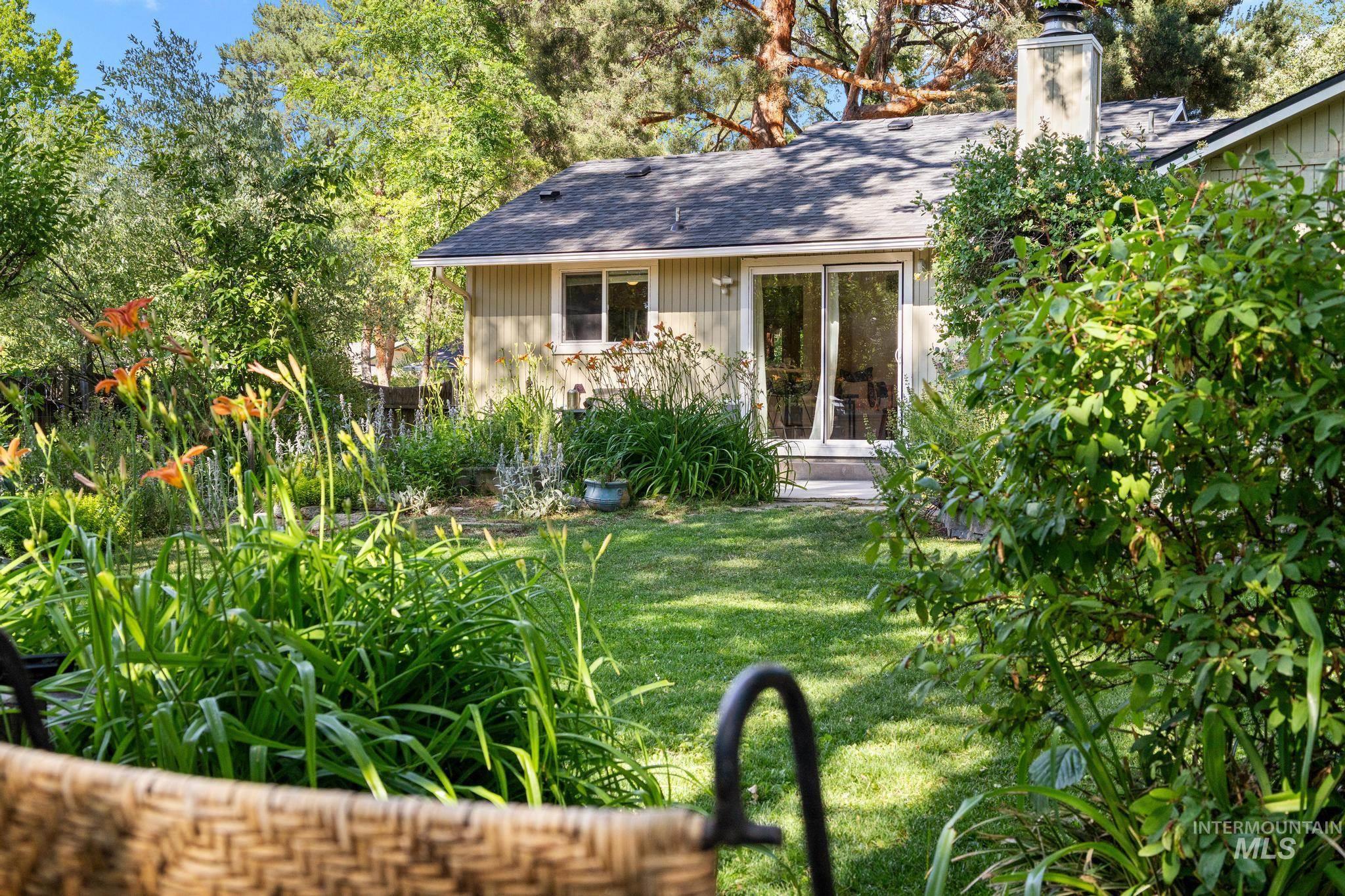 Expansive grassy backyard featuring mature plantings and a variety of flowering shrubs