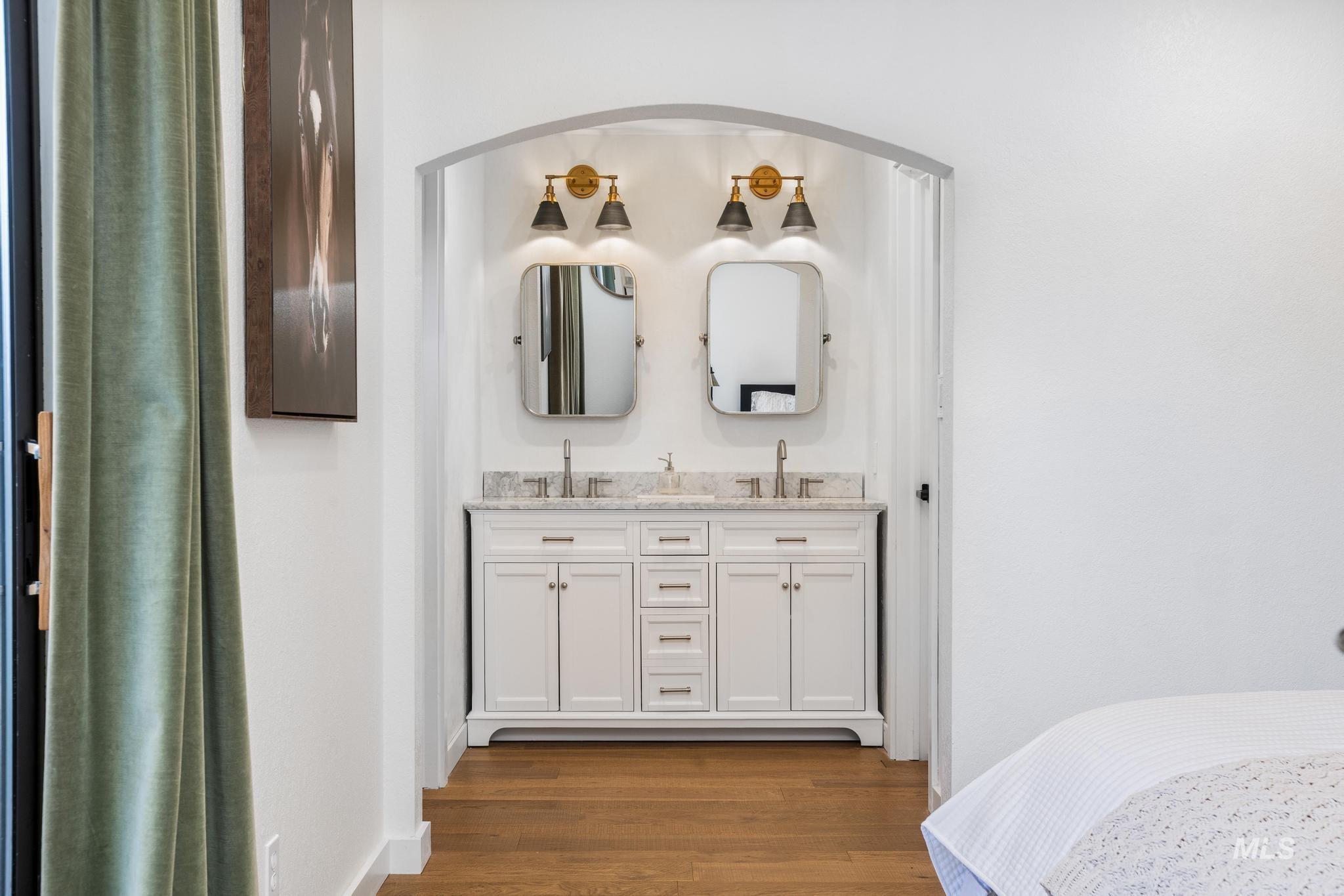Double vanity with a light-toned countertop, dual rectangular mirrors, and a pair of brass-finish two-light sconces