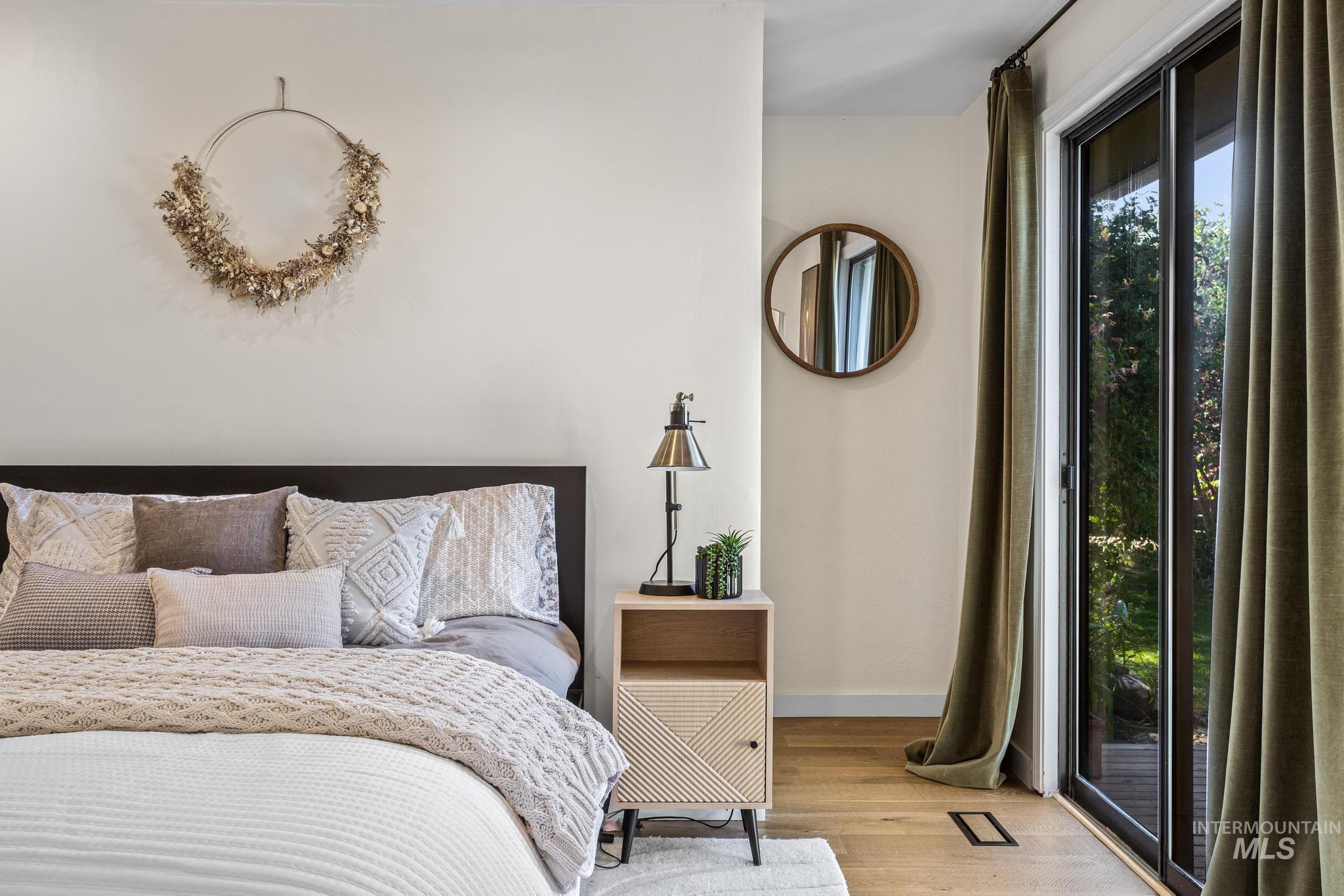 Bedroom featuring warm wood-finish flooring, a contemporary dark wood headboard, and a built-in sliding glass door