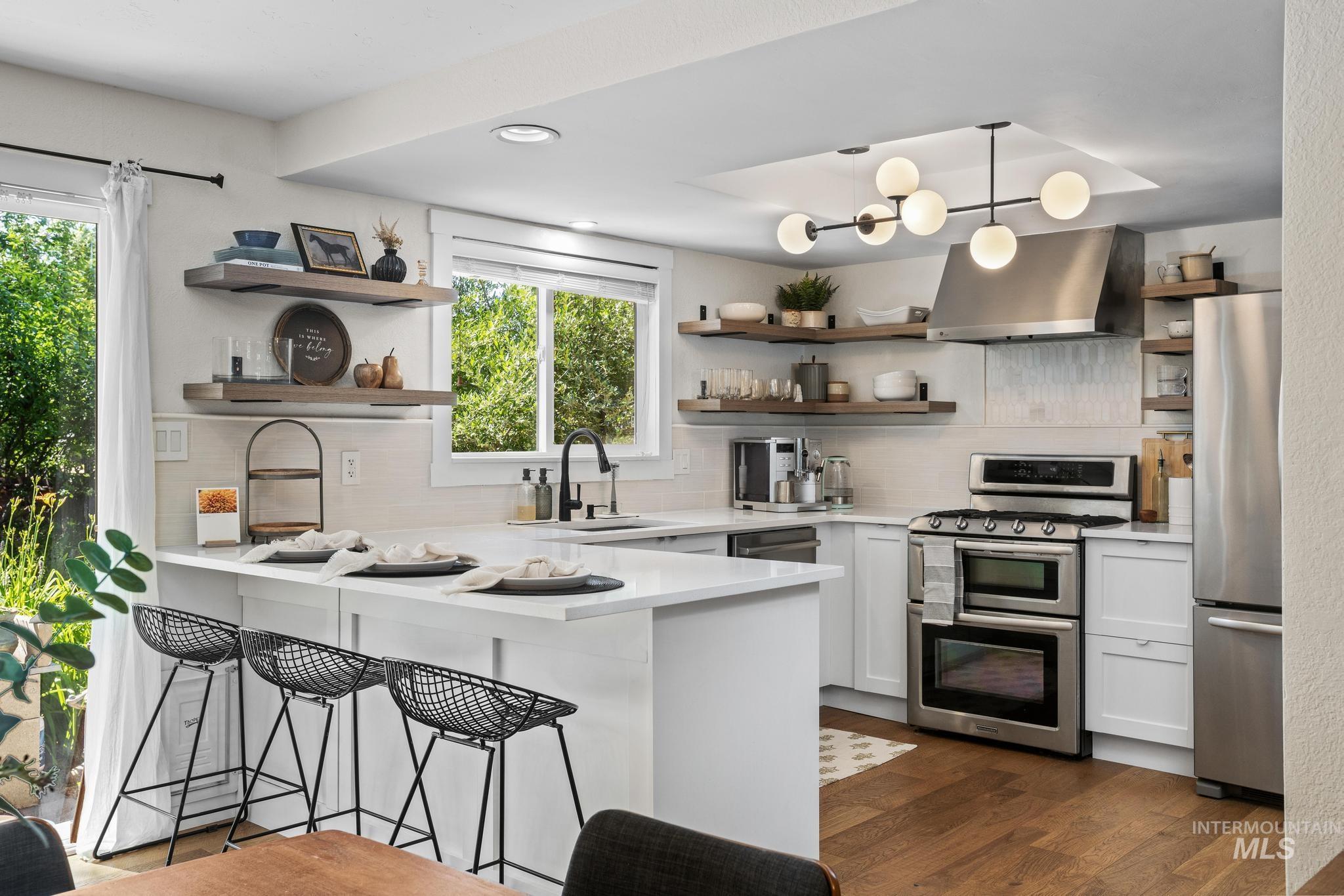 Contemporary kitchen with white cabinetry, stainless steel appliances, and wood-finish flooring