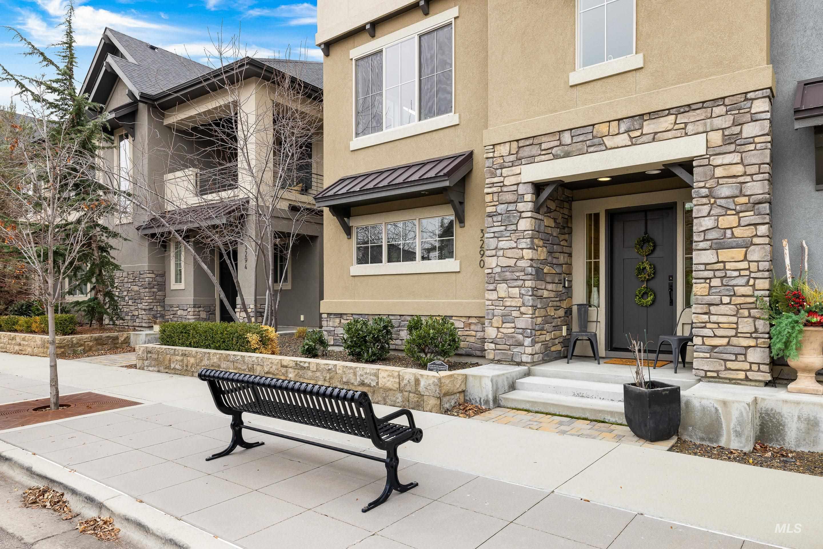 Entrance to property featuring stone siding, stucco siding, a metal roof, and a standing seam roof