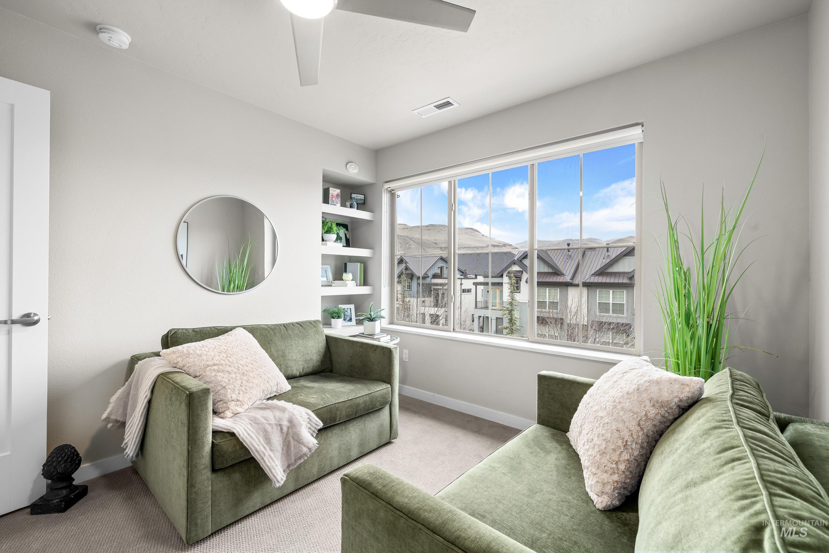 Carpeted living room with built in features and a ceiling fan