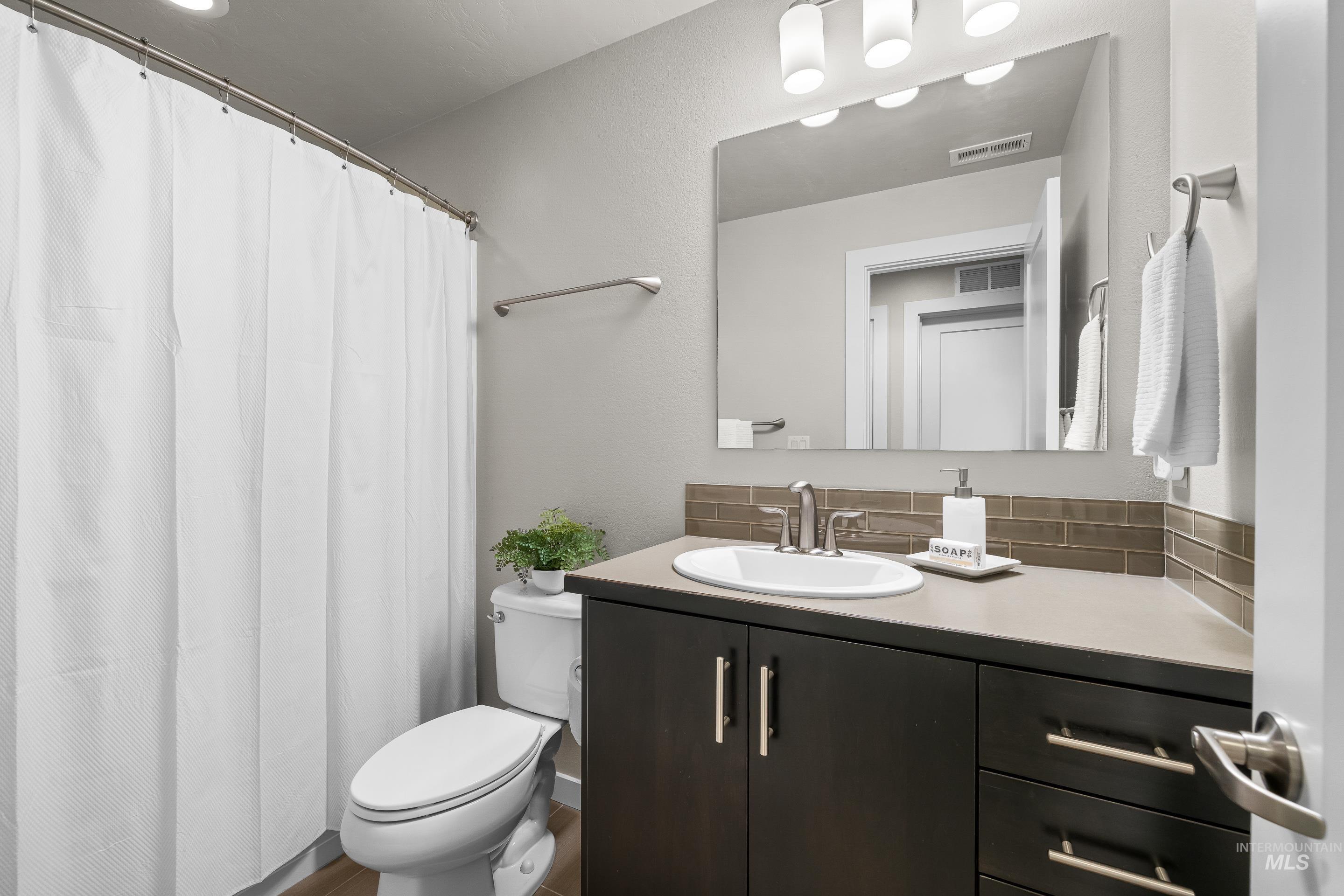 Bathroom with vanity, curtained shower, and tasteful backsplash