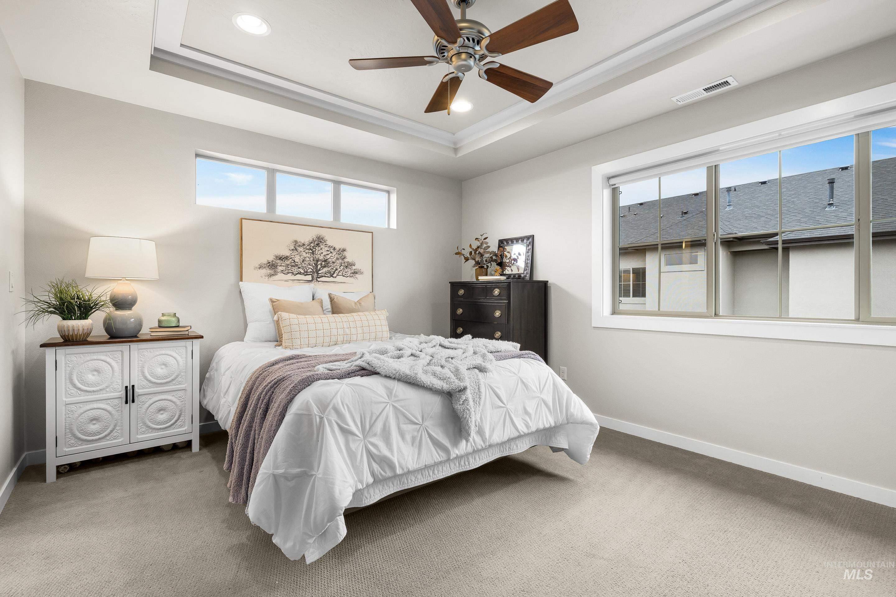 Carpeted bedroom with a tray ceiling, ceiling fan, and recessed lighting