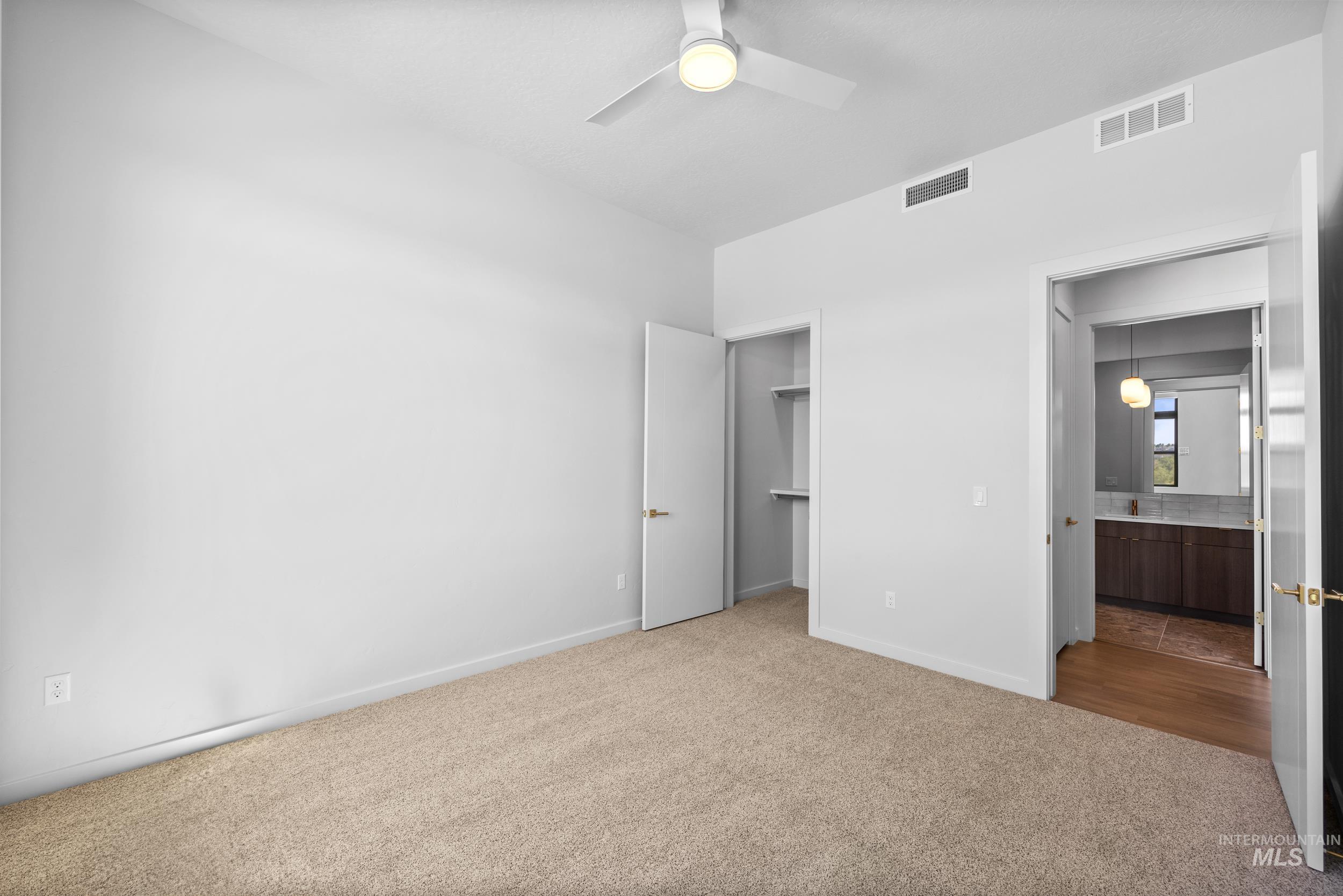 Unfurnished bedroom with carpet flooring, a ceiling fan, and ensuite bathroom