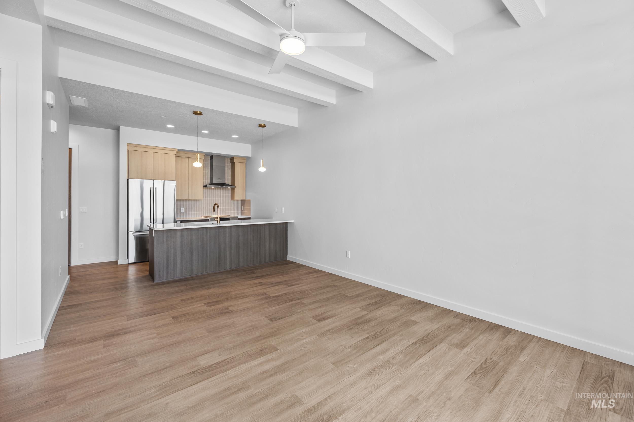 Kitchen featuring a peninsula, open floor plan, light countertops, light wood-style flooring, and freestanding refrigerator
