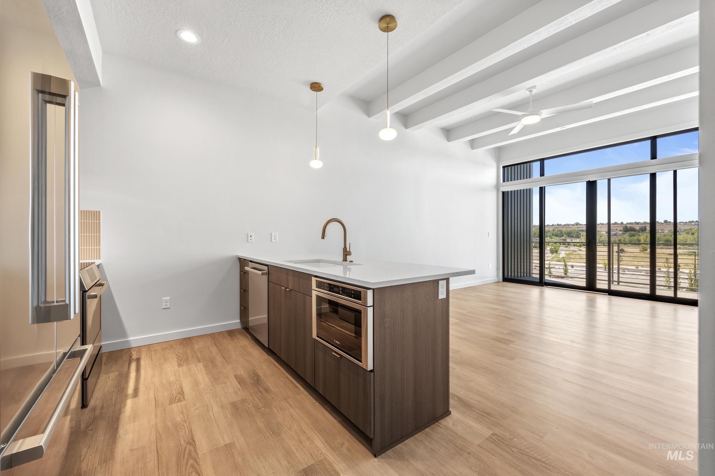 Kitchen with a peninsula, modern cabinets, light wood-type flooring, a wall of windows, and pendant lighting