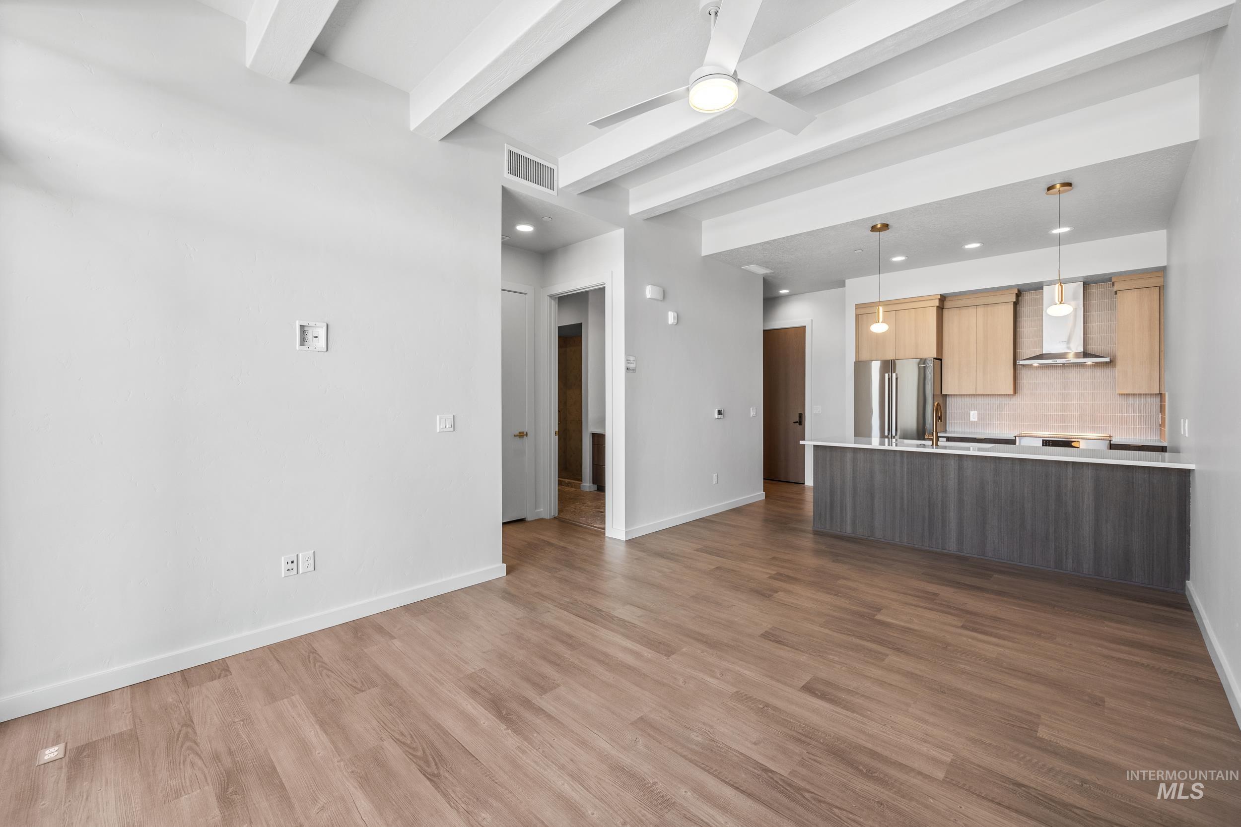 Unfurnished living room featuring beam ceiling, dark wood-type flooring, a ceiling fan, and recessed lighting