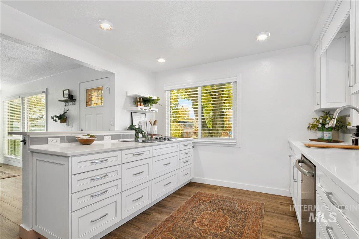 Kitchen featuring white cabinets, a peninsula, light stone countertops, dark wood-style flooring, and a textured ceiling