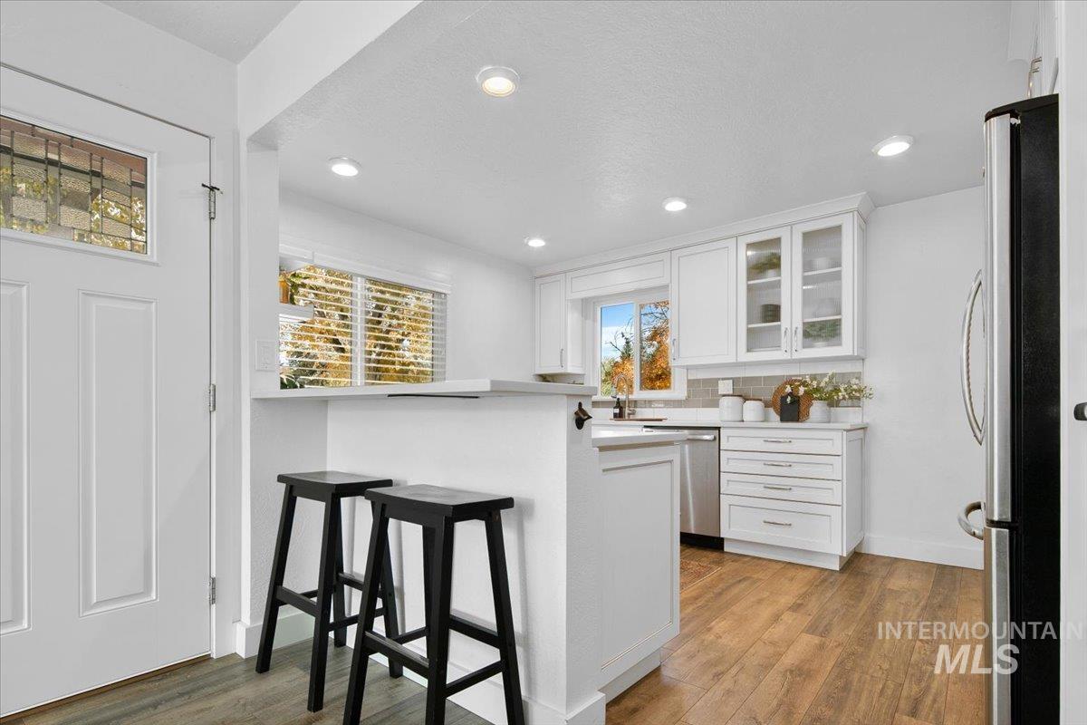 Kitchen featuring light countertops, white cabinetry, a breakfast bar area, appliances with stainless steel finishes, and light wood-style flooring