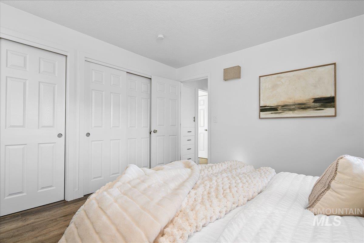 Bedroom with dark wood-style floors, multiple closets, and a textured ceiling