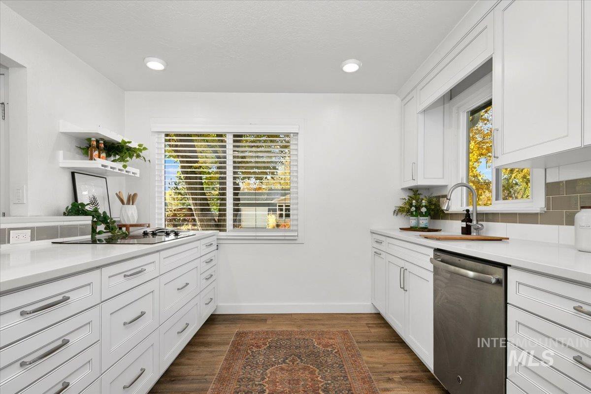 Kitchen with white cabinetry, dark wood finished floors, dishwasher, light stone countertops, and recessed lighting