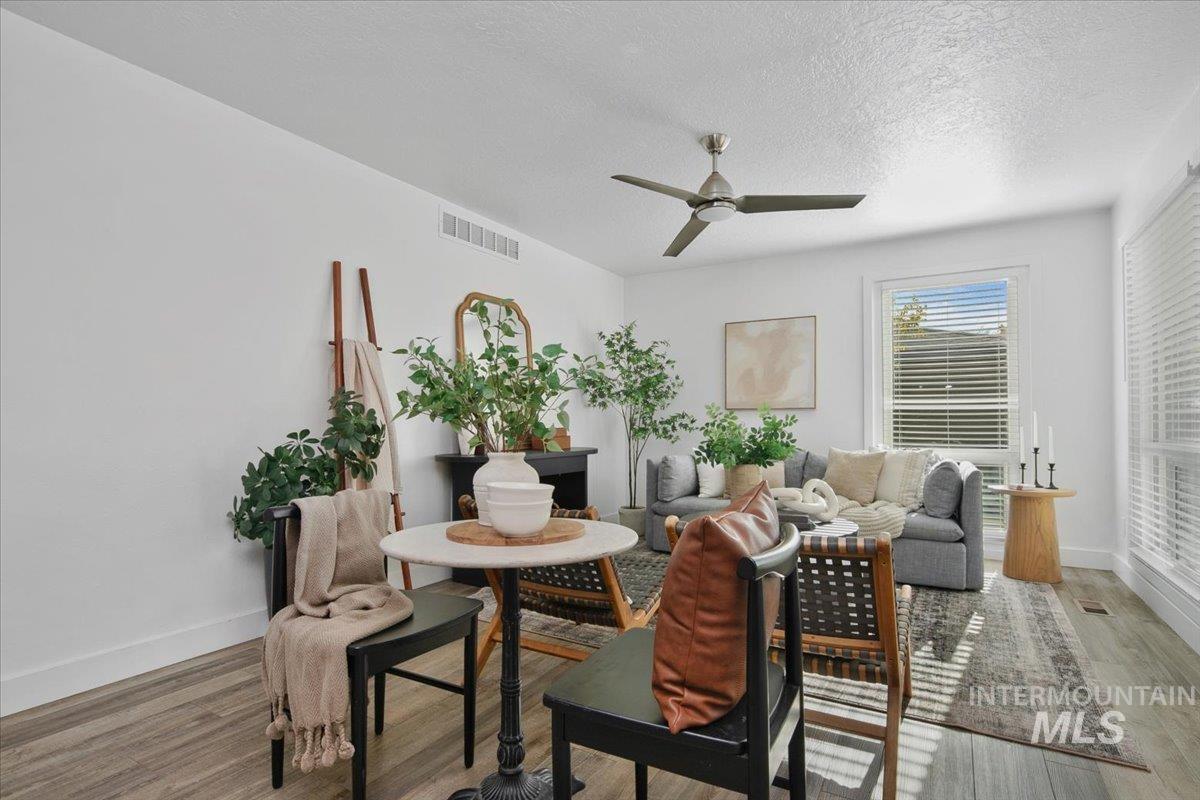 Living area featuring a textured ceiling, light wood-type flooring, and a ceiling fan