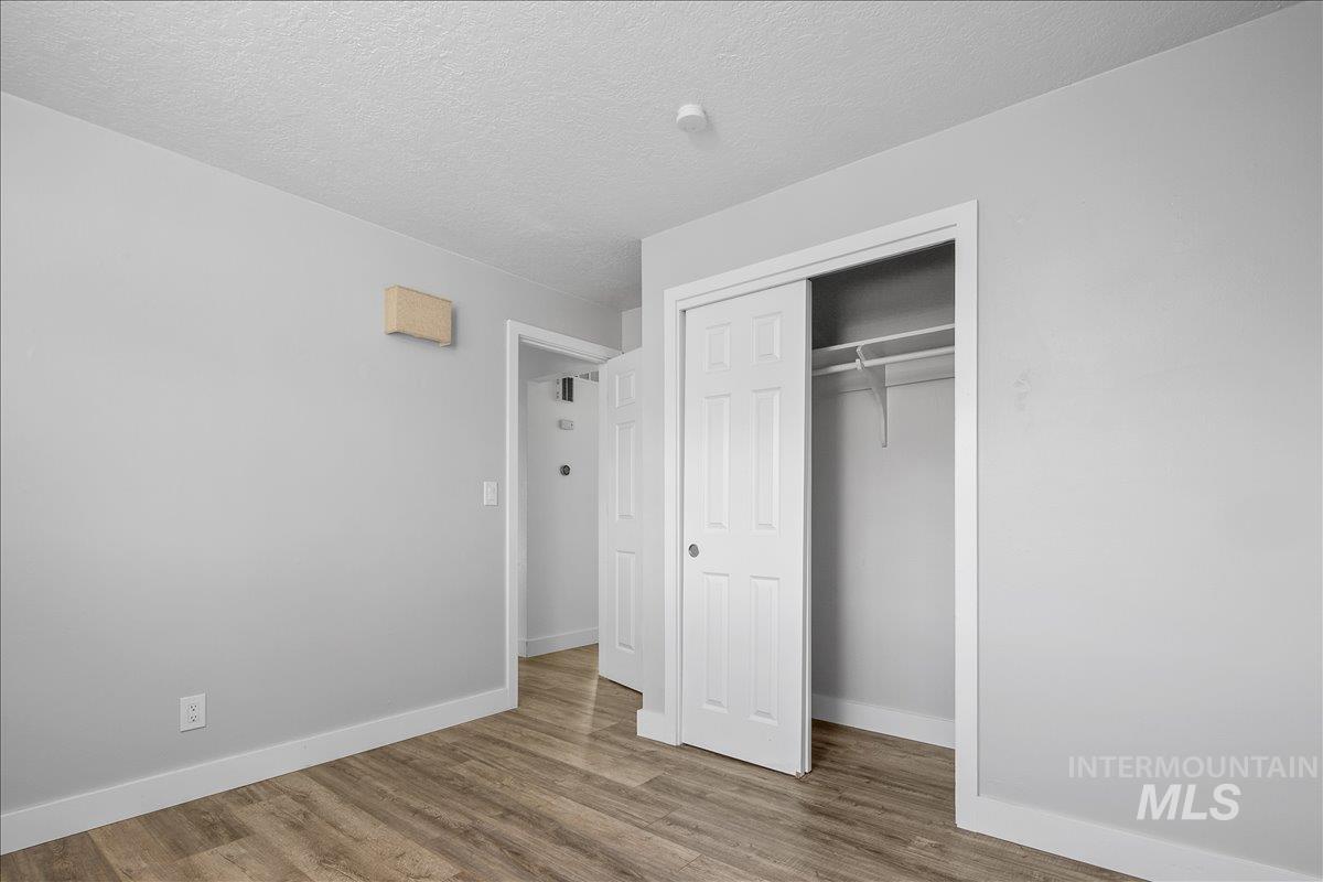 Unfurnished bedroom with a textured ceiling, wood finished floors, and a closet