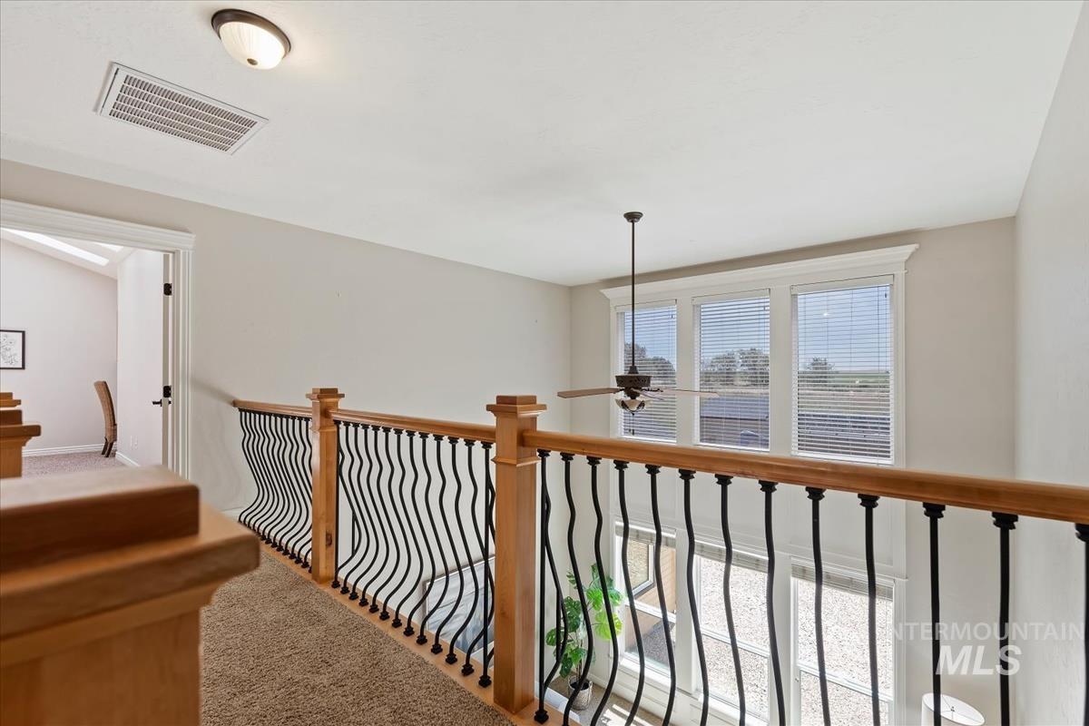 Upper-level landing featuring a wood handrail with decorative black iron balusters