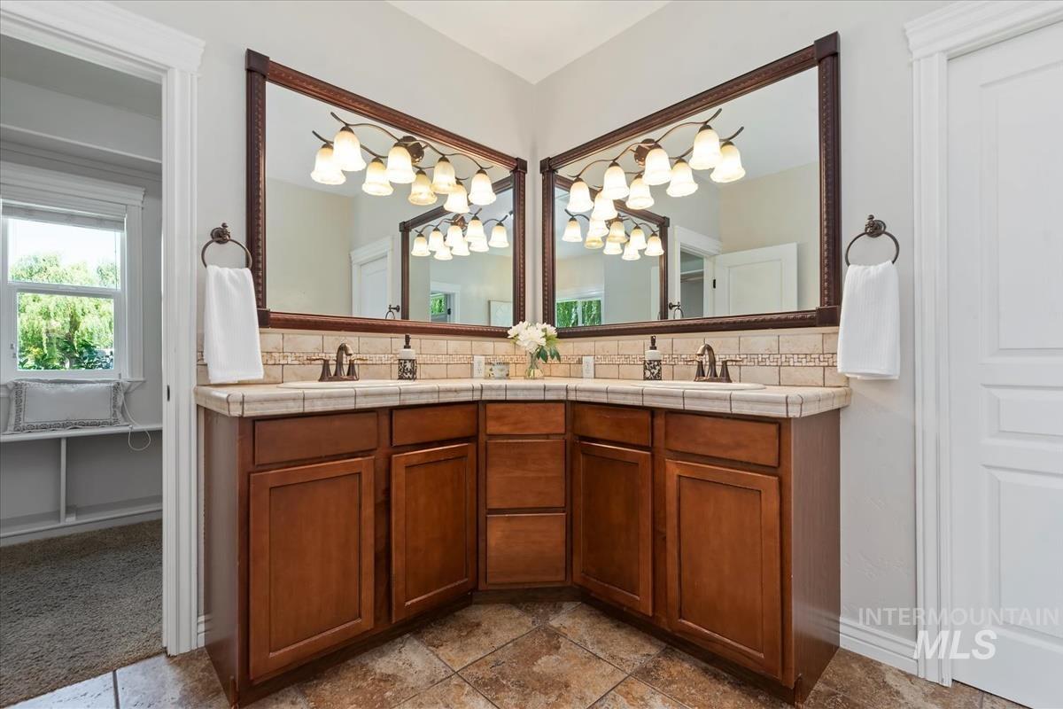 Dual vanity featuring wood cabinetry, tile countertops, and a full tile backsplash