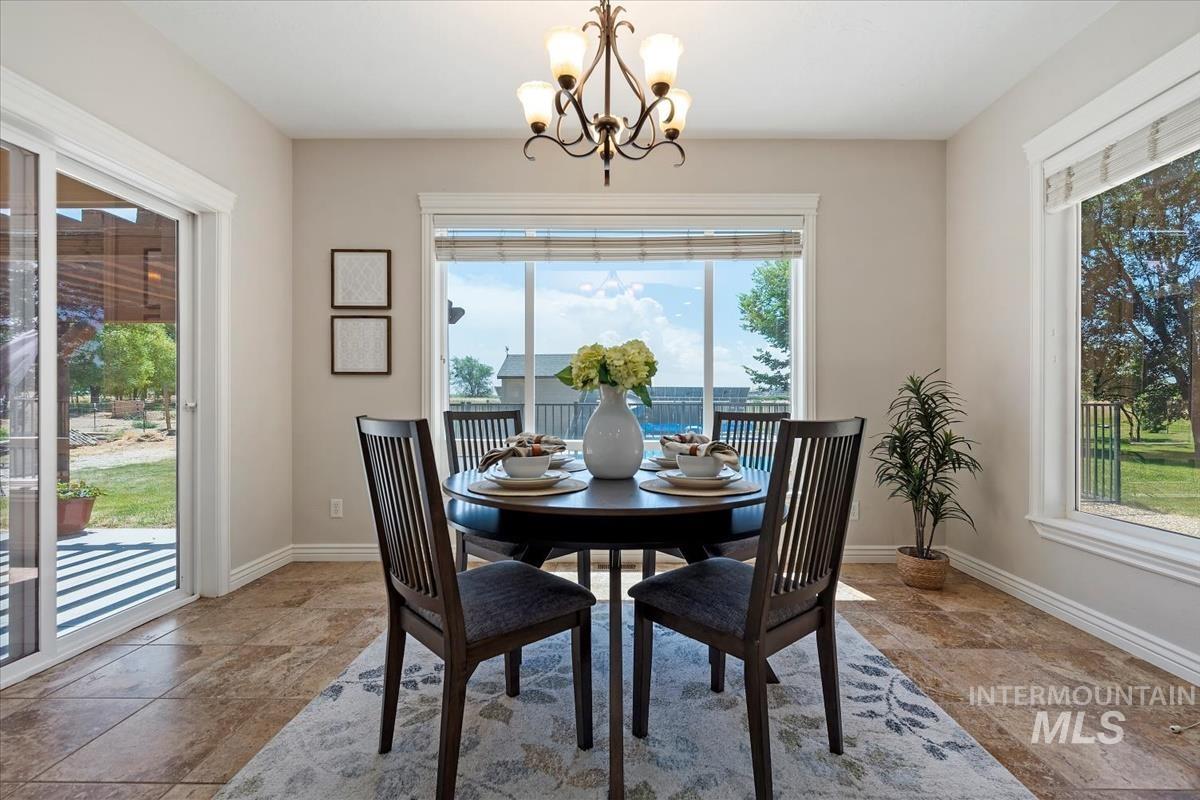 Dining area featuring tile flooring, a large picture window, a sliding glass door to the exterior, a multi-light chandelier, and trim molding