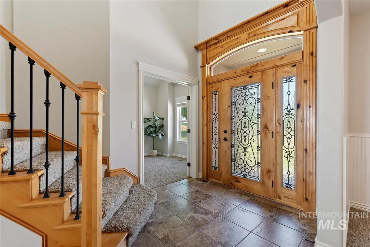 Grand entryway featuring a wood door with decorative glass inserts, a coordinating arched transom, and tile flooring