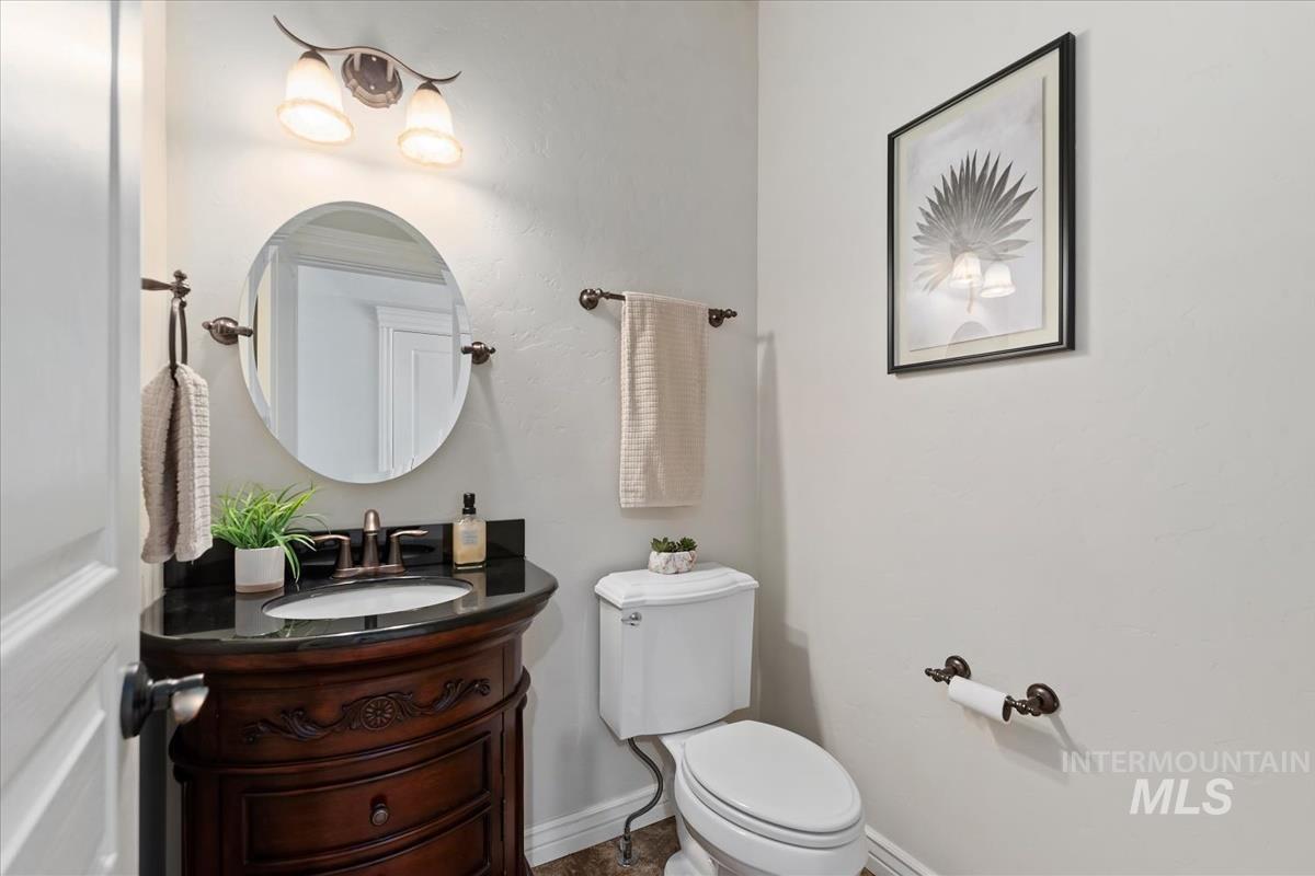 Powder room featuring a dark wood vanity with carved details, a black stone countertop, and an oval mirror