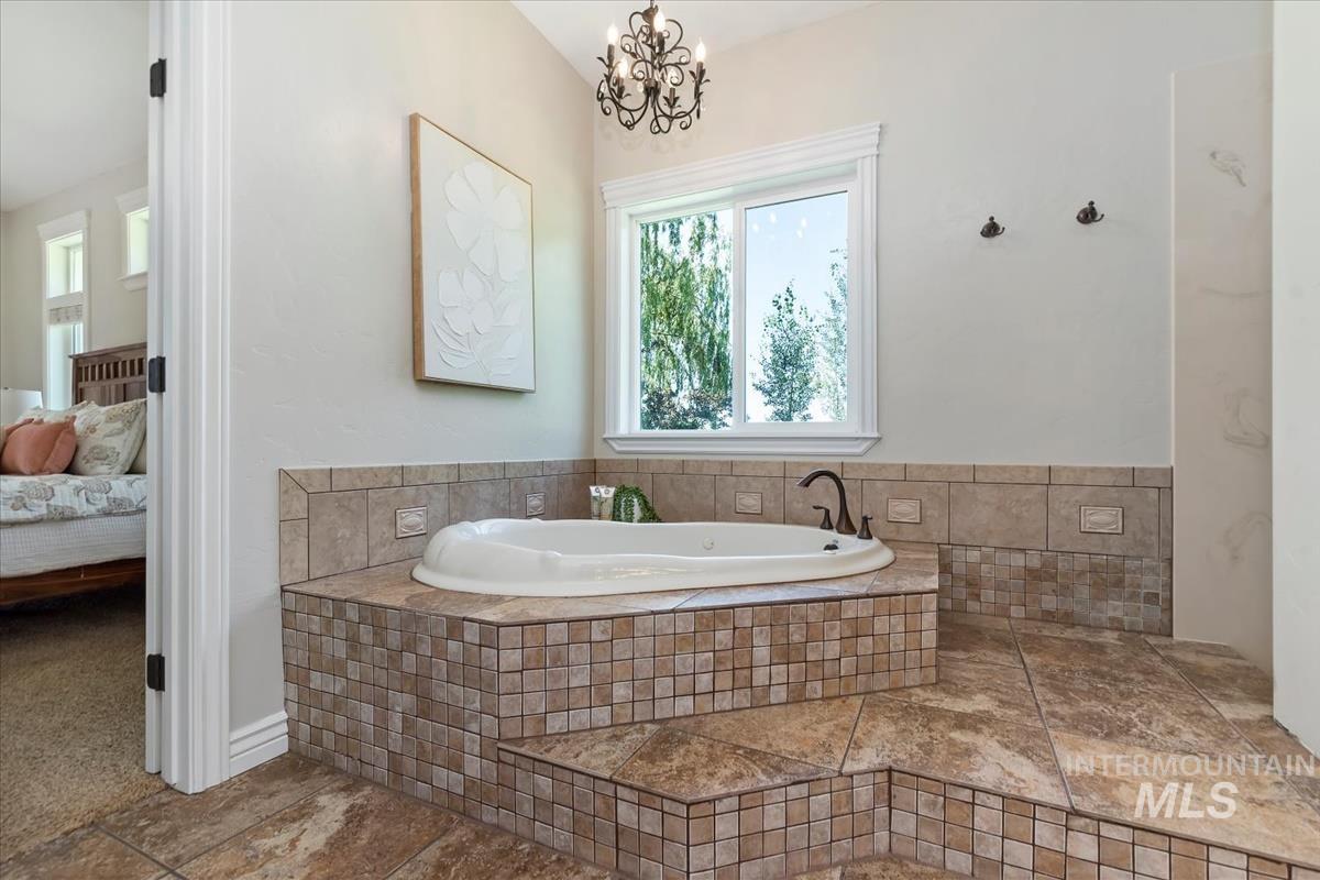 Soaking tub with a bronze-finish faucet, surrounded by mosaic and large-format tile