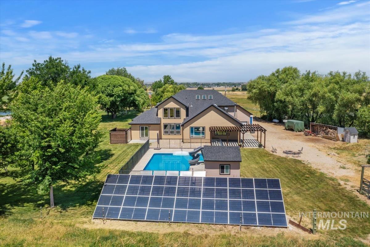 Contemporary residence with a fenced swimming pool, adjacent pool house, and a large solar panel array
