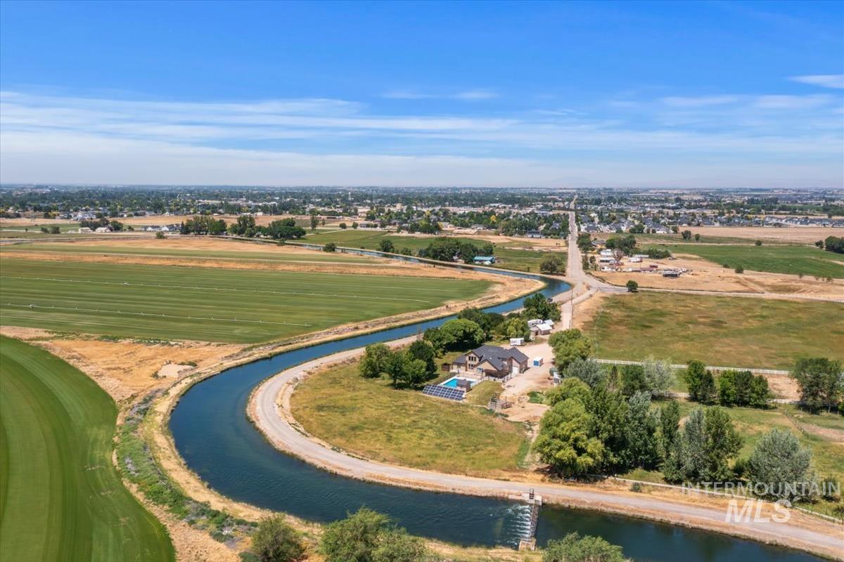 Aerial view showcasing a curved waterway bordering green and golden fields
