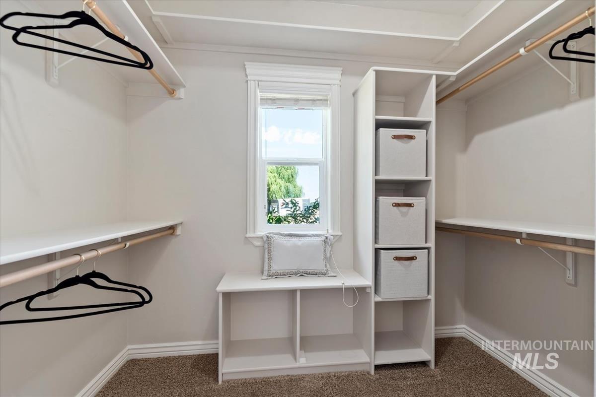 Walk-in closet featuring built-in shelving, hanging rods, and a window for natural light